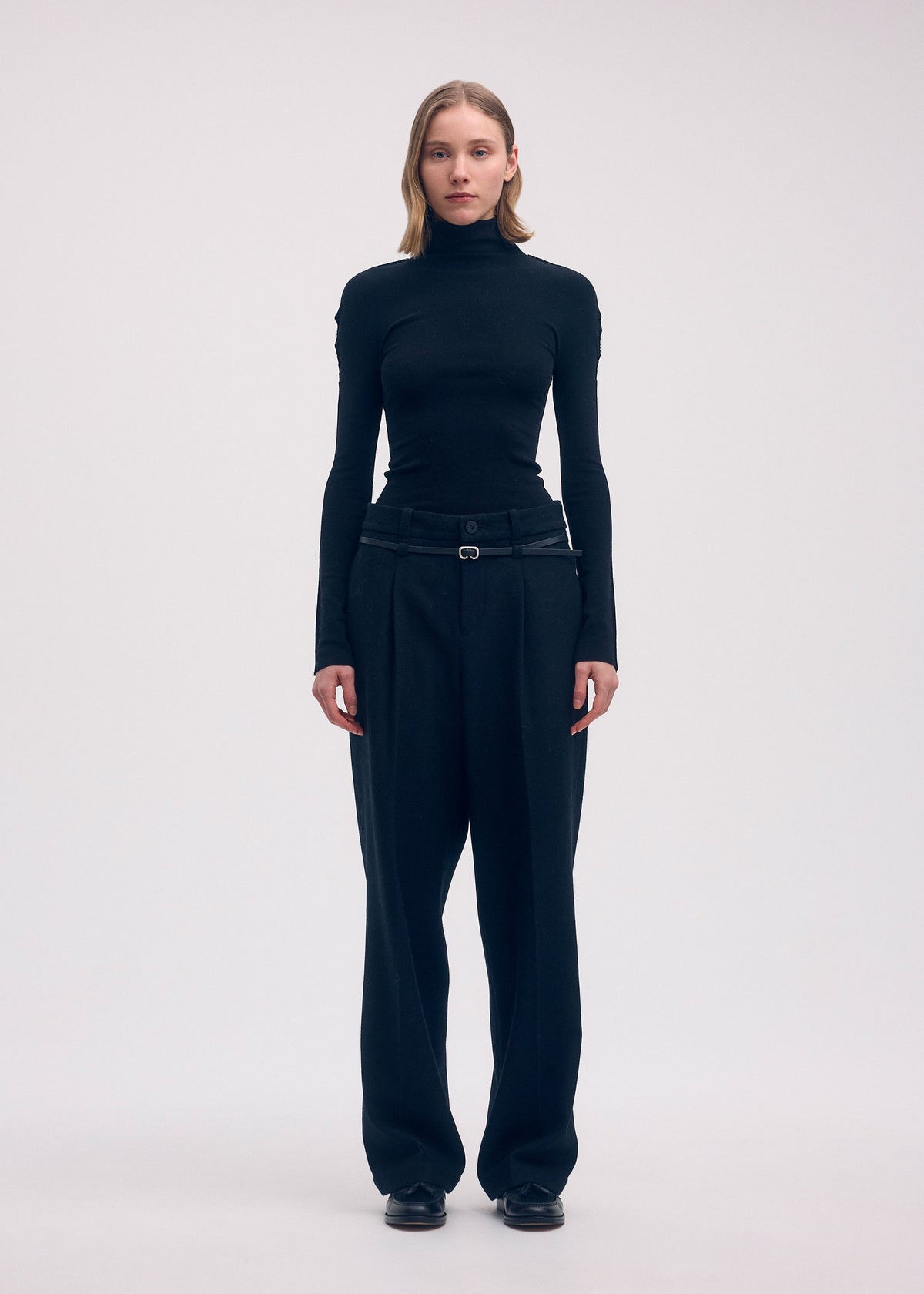 A model wears the Issey Miyake WOOL TWEED PANTS trousers.