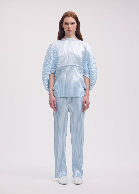 A model wears the Issey Miyake GLOSSED METAL PLEATS trousers.