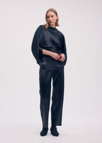 A model wears the Issey Miyake GLOSSED METAL PLEATS trousers.