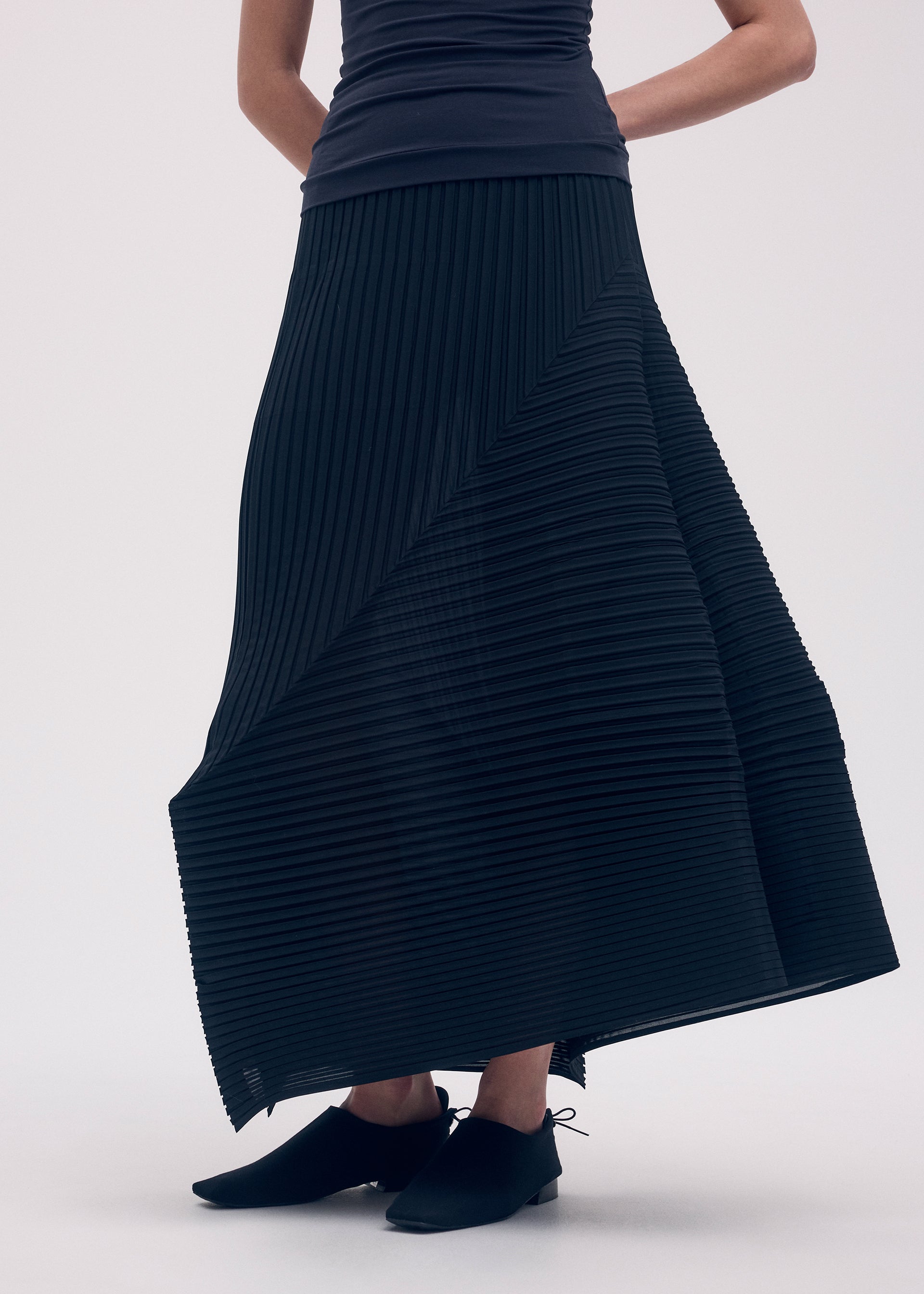A model wears the ISSEY MIYAKE FOLD PLEATS skirt.