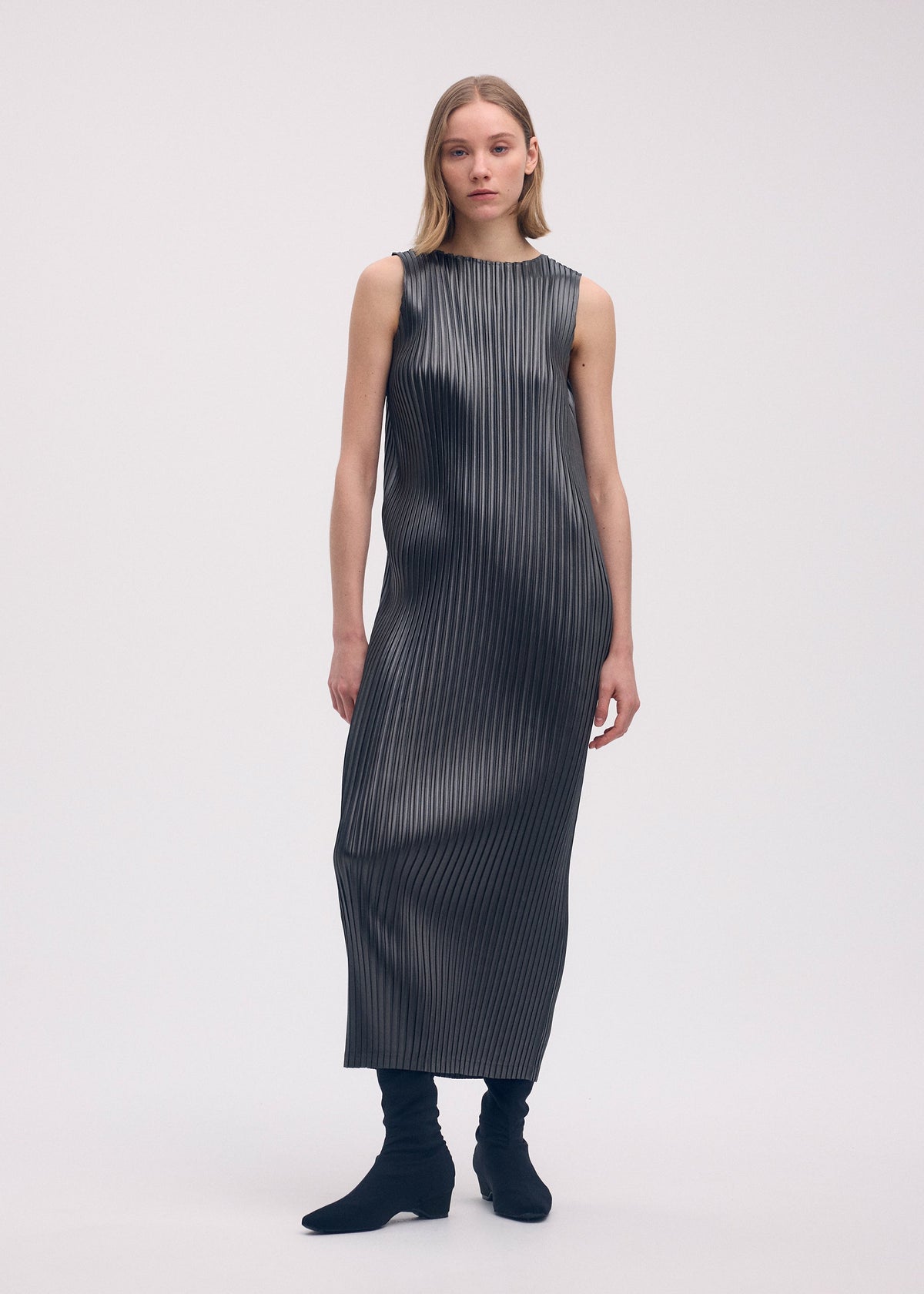 A model wears the Issey Miyake GLOSSED METAL PLEATS dress.