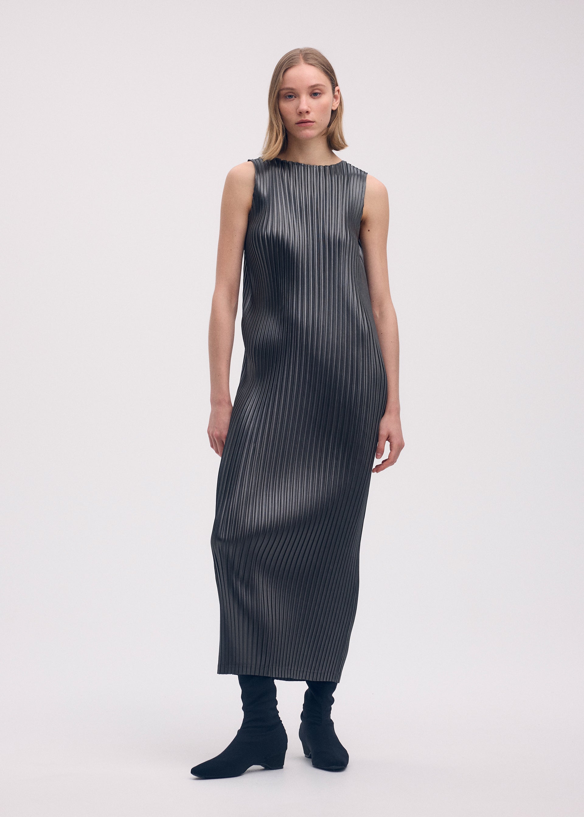 A model wears the Issey Miyake GLOSSED METAL PLEATS dress.