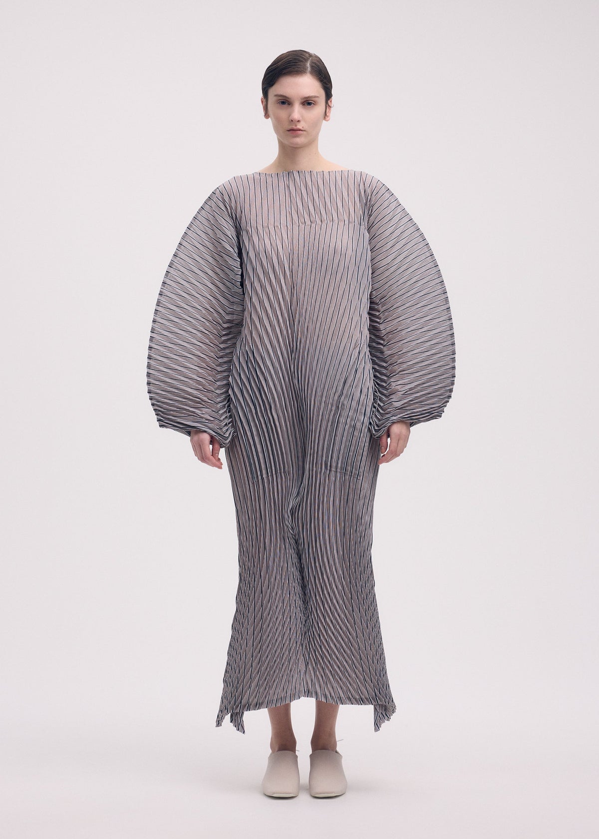 A model wears the Issey Miyake GENERIC STRIPES HAND PLEATS dress.