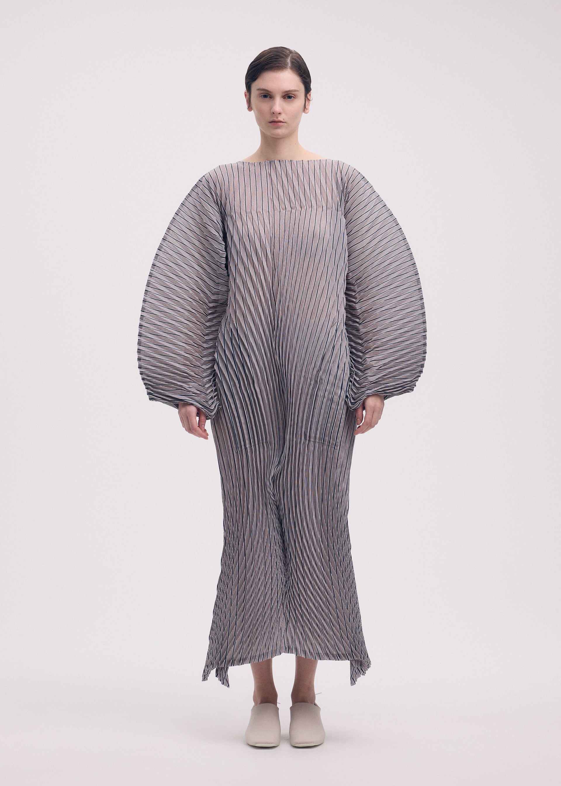 A model wears the Issey Miyake GENERIC STRIPES HAND PLEATS dress.