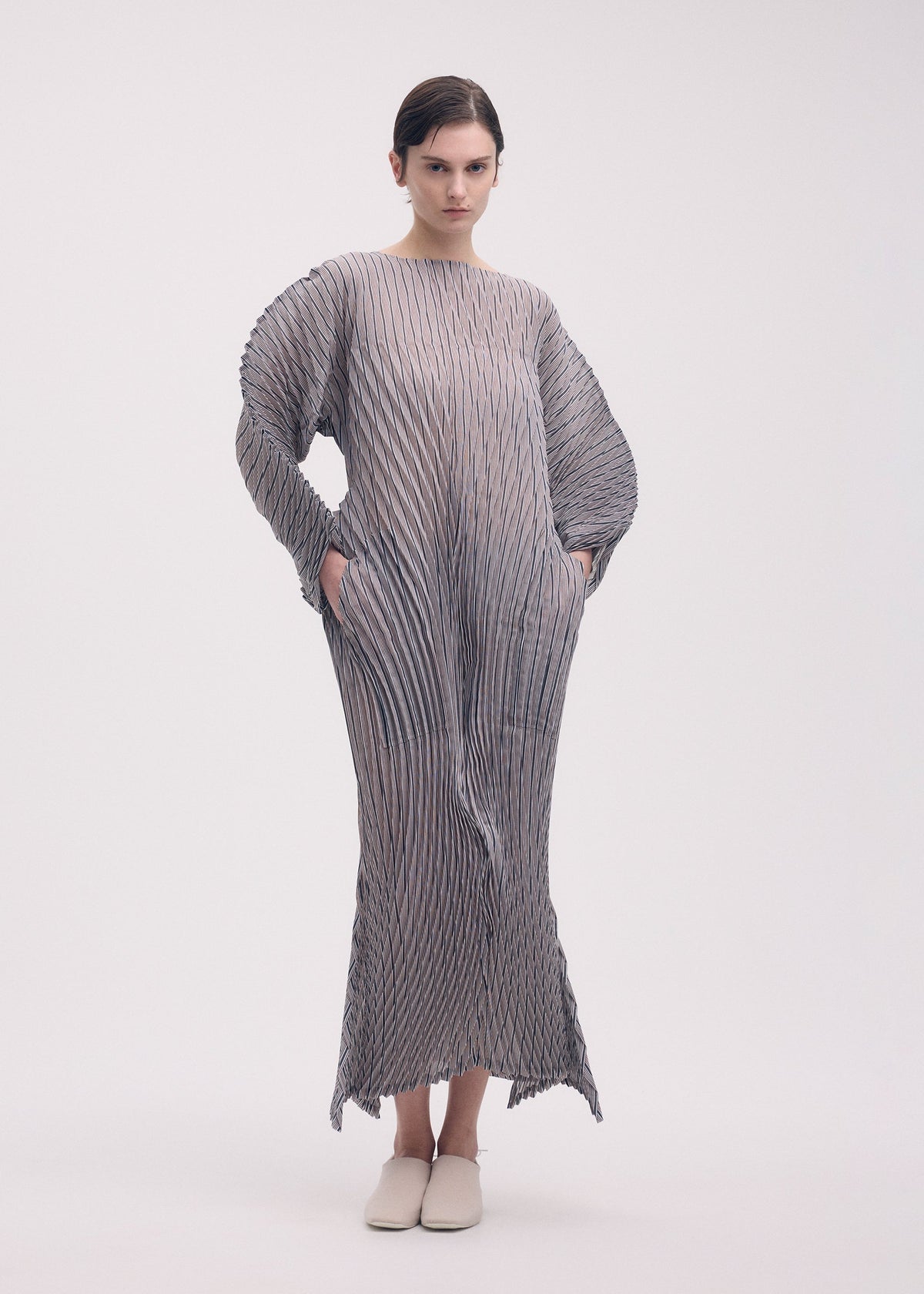 A model wears the Issey Miyake GENERIC STRIPES HAND PLEATS dress.