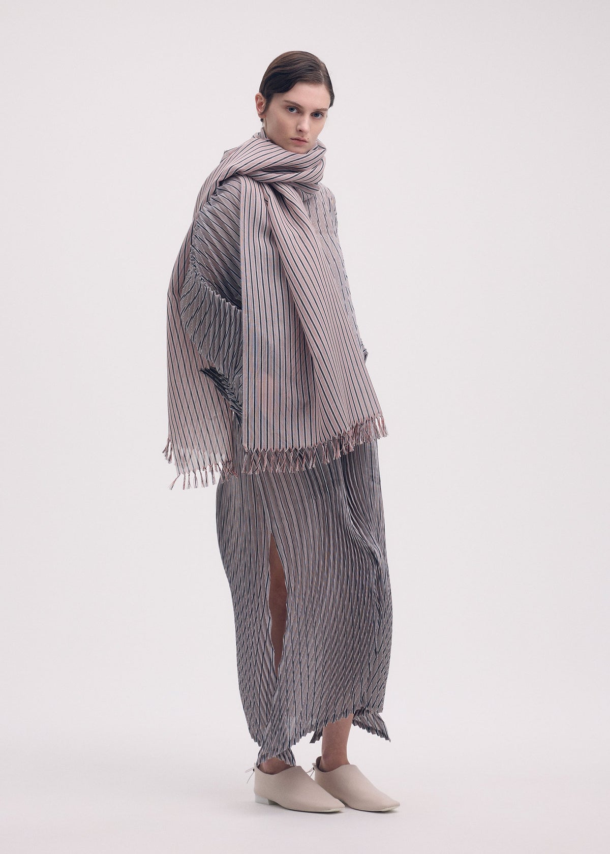 A model wears the Issey Miyake GENERIC STRIPES HAND PLEATS dress.