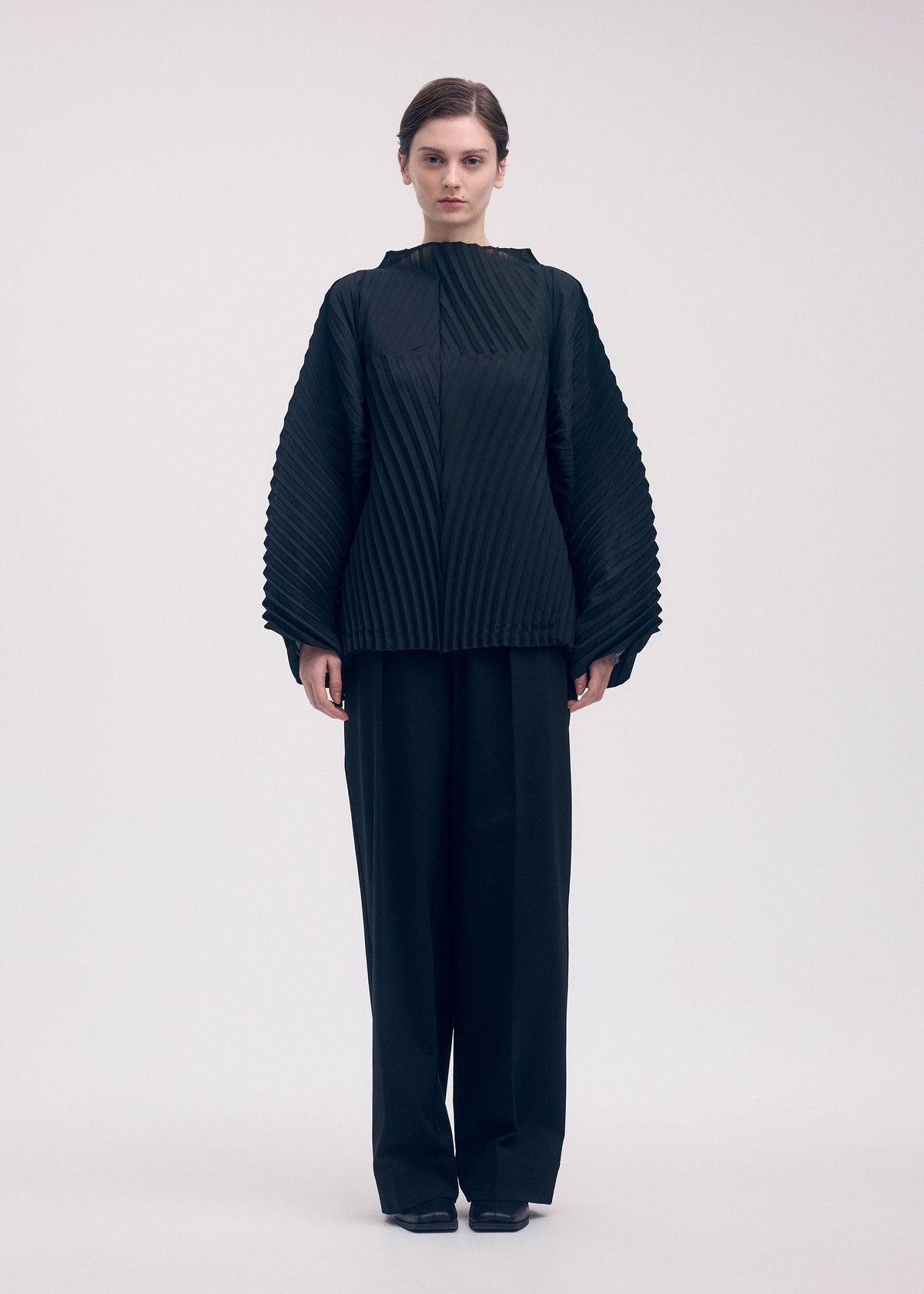 A model wears the ISSEY MIYAKE WAVE PLEATS shirt.