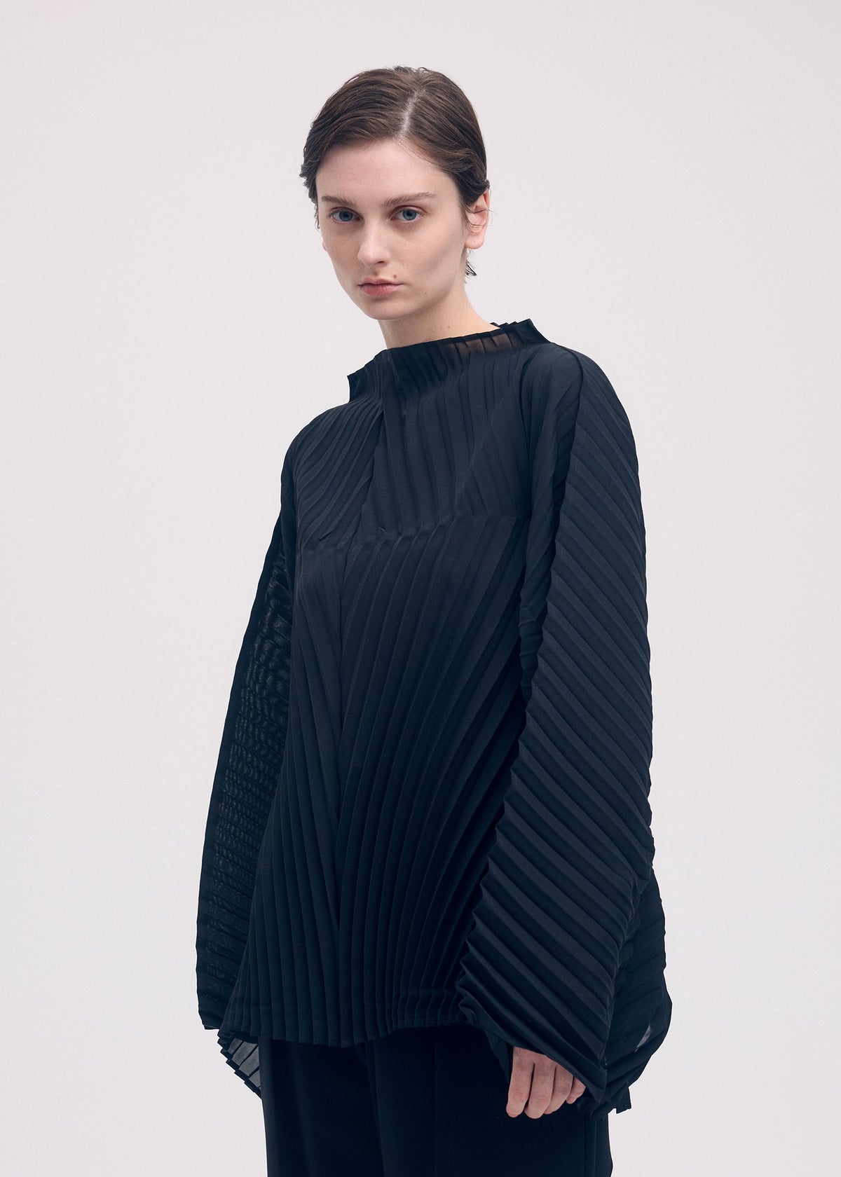 A model wears the ISSEY MIYAKE WAVE PLEATS shirt.