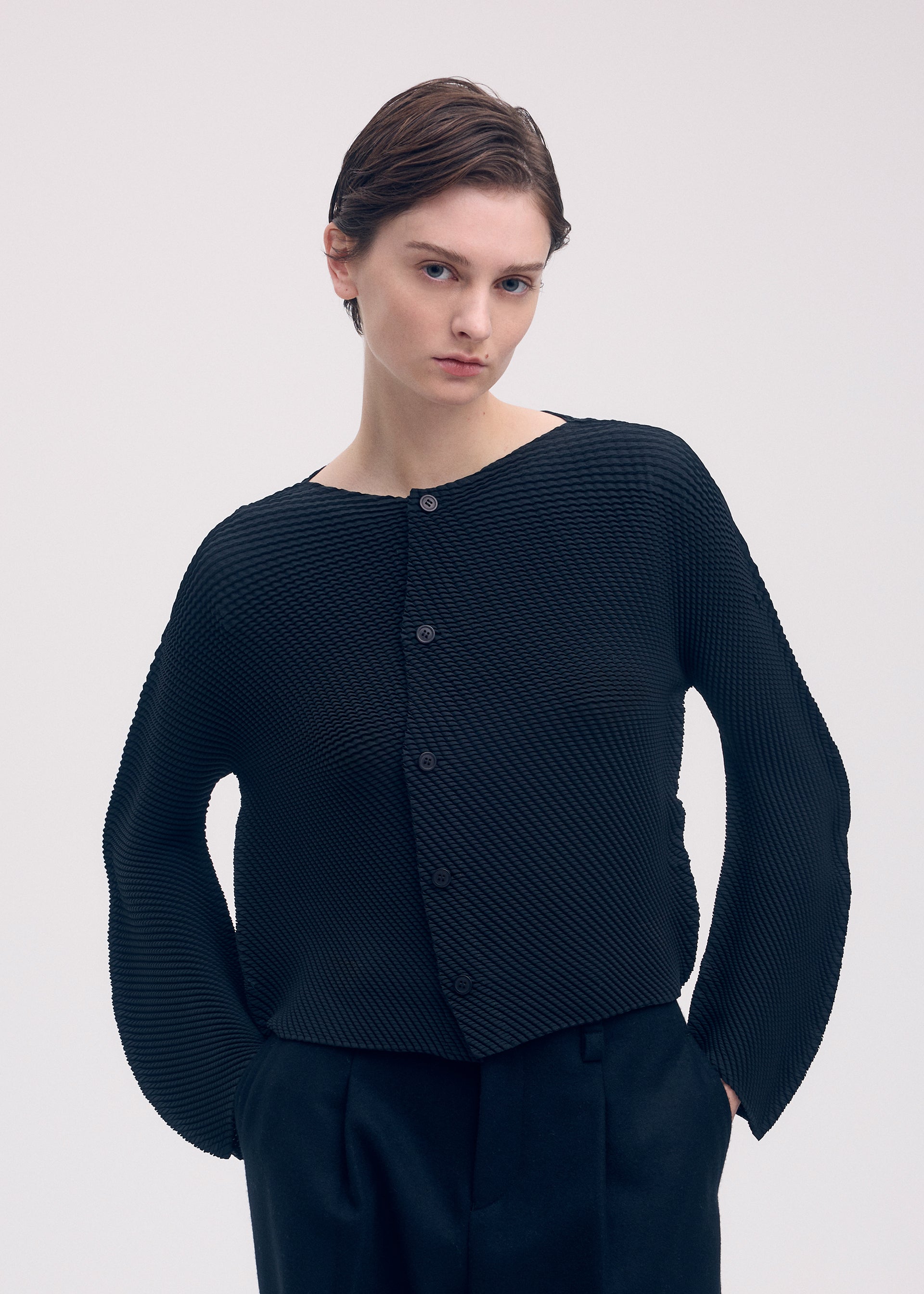 A model wears the Issey Miyake SHIFTED MISTY PLEATS cardigan.