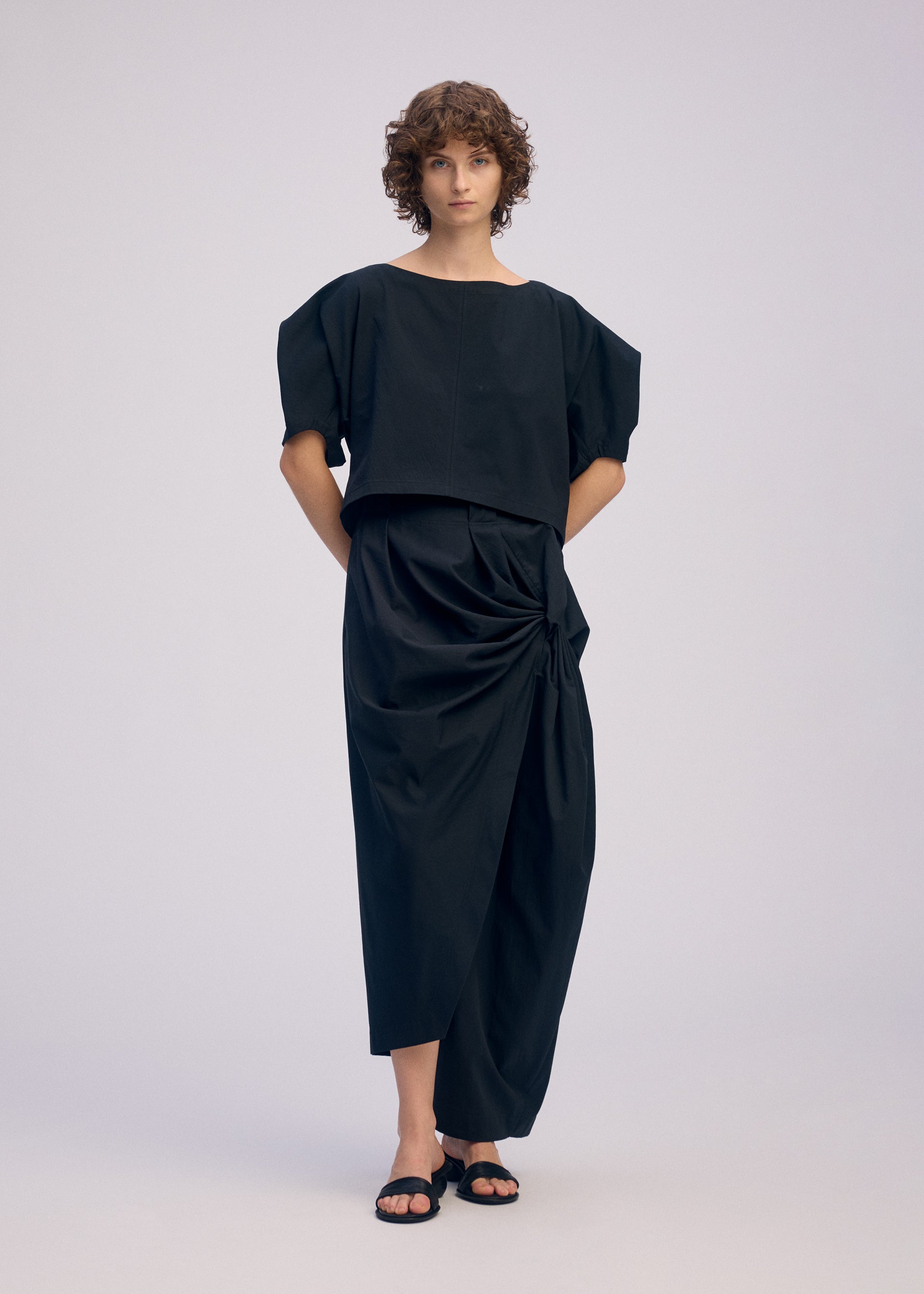 A model wears the ISSEY MIYAKE TWISTED DRAPE pants.