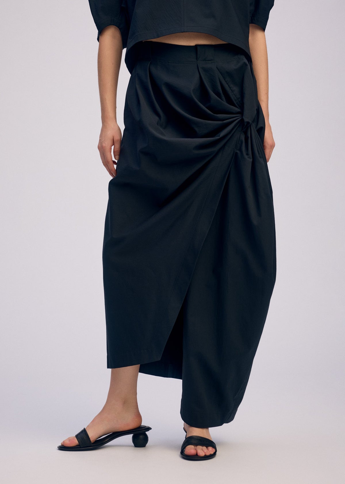 A model wears the ISSEY MIYAKE TWISTED DRAPE pants.