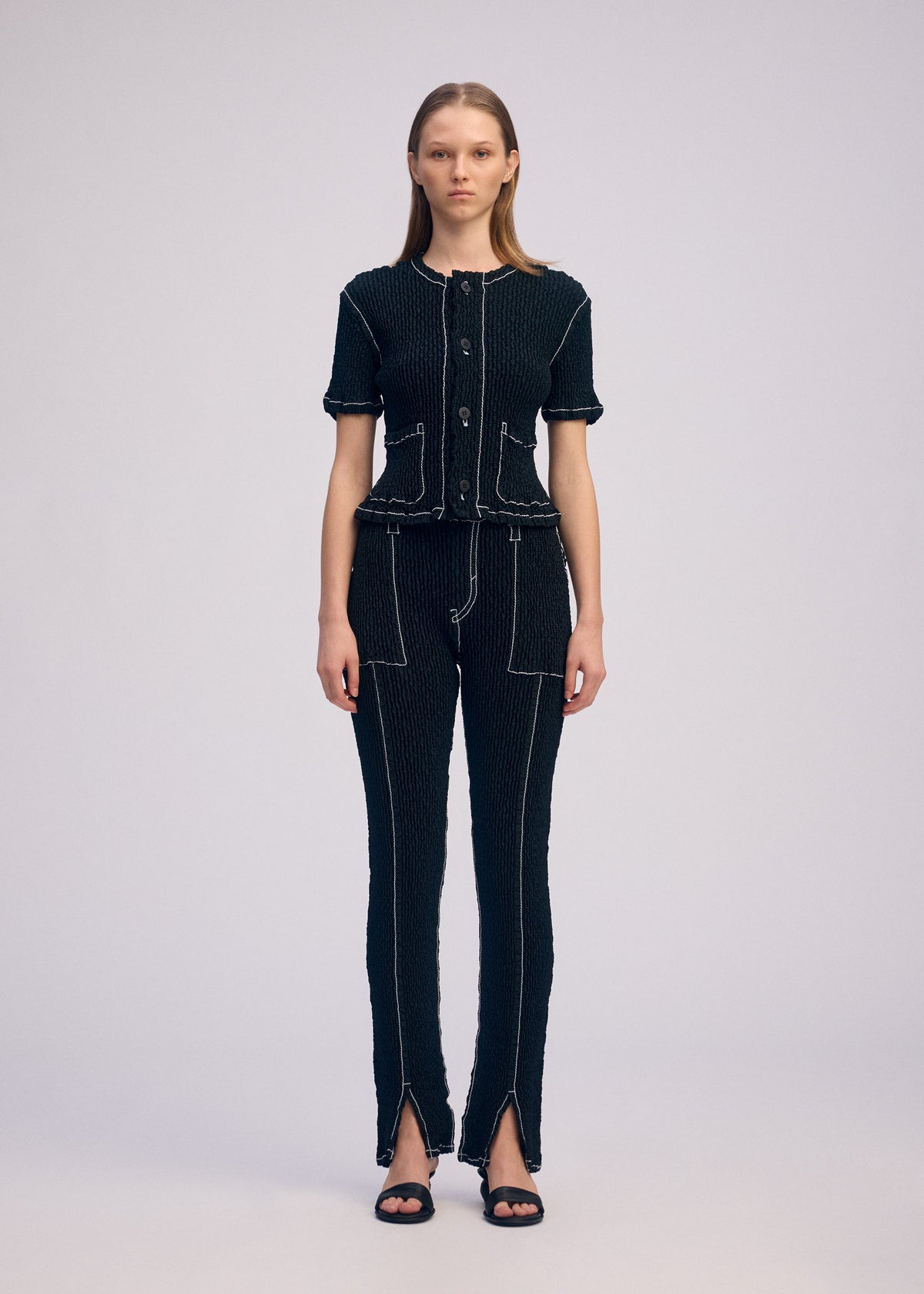 A model wears the ISSEY MIYAKE WAVELET ENSEMBLE pants.