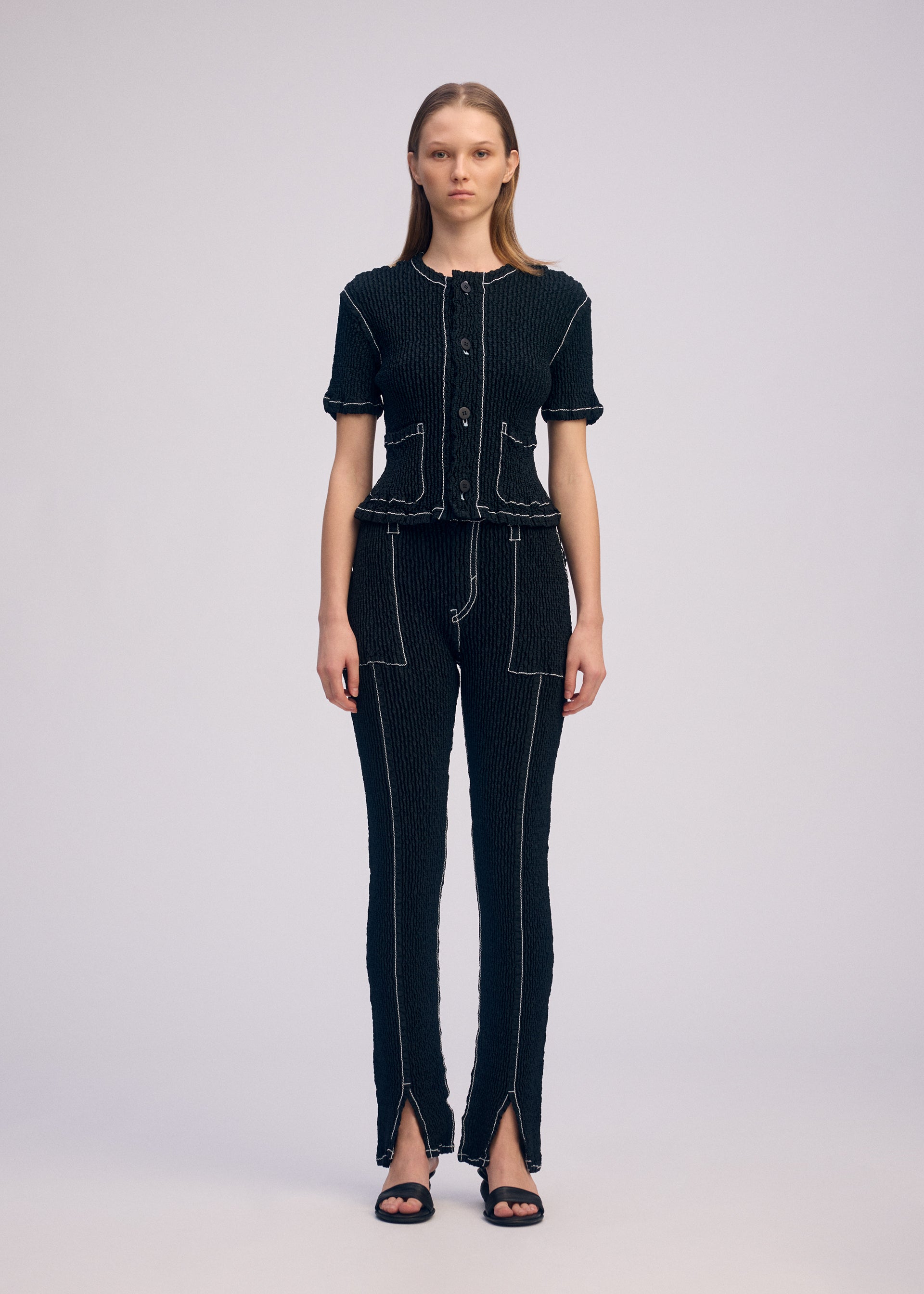 A model wears the ISSEY MIYAKE WAVELET ENSEMBLE pants.