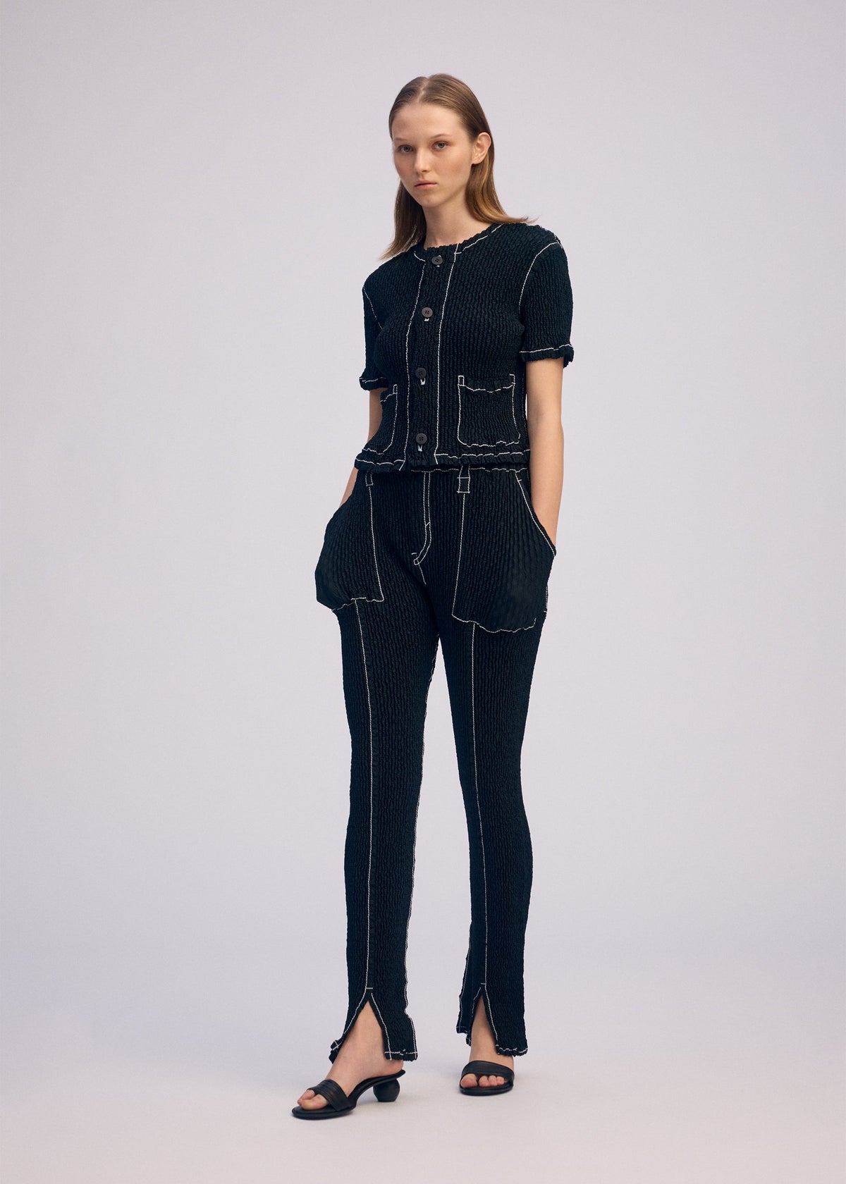 A model wears the ISSEY MIYAKE WAVELET ENSEMBLE pants.