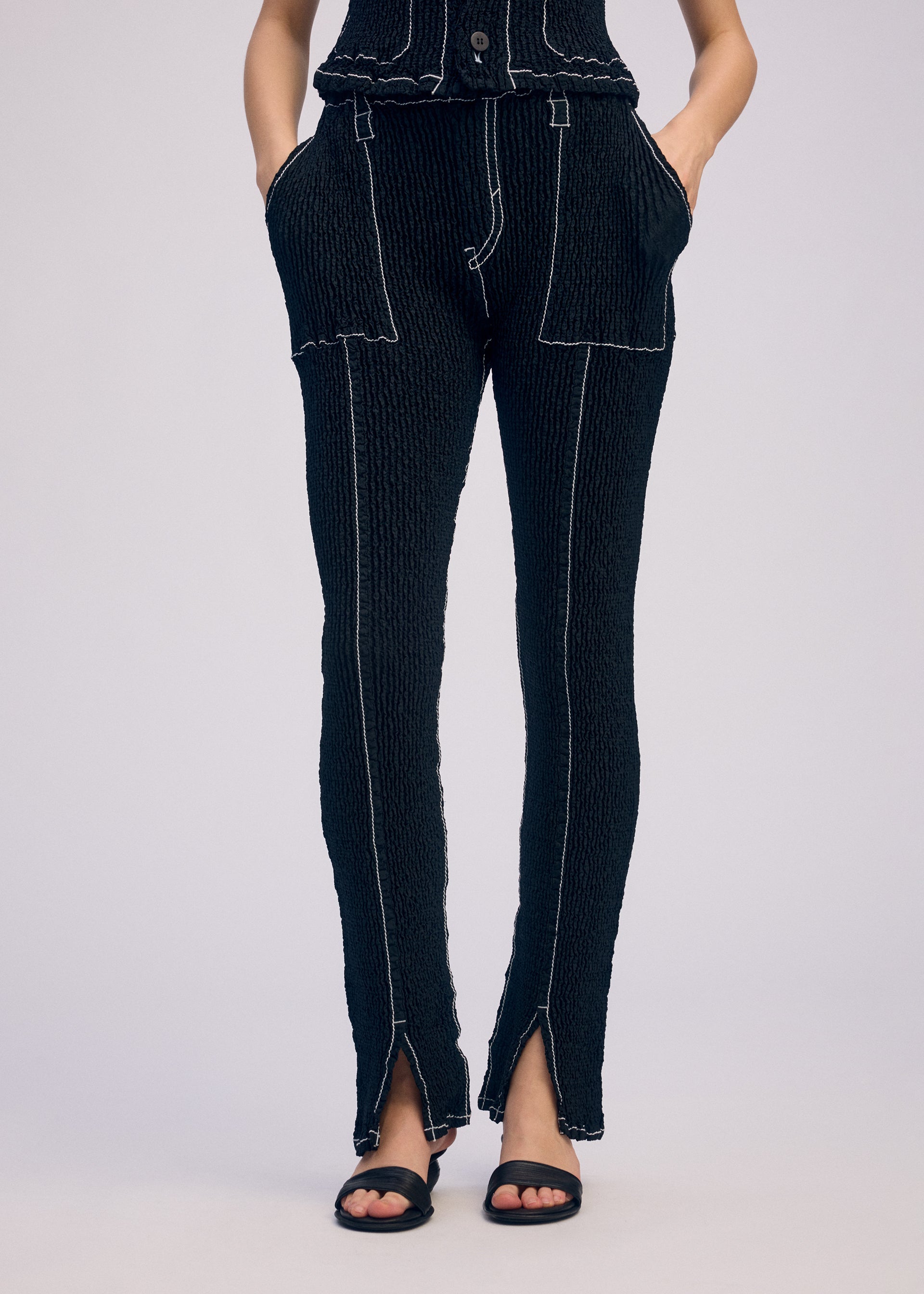 A model wears the ISSEY MIYAKE WAVELET ENSEMBLE pants.