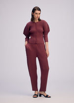 A model wears the ISSEY MIYAKE SLEEK PLEATS sleek-pleats-pants-burgundy.