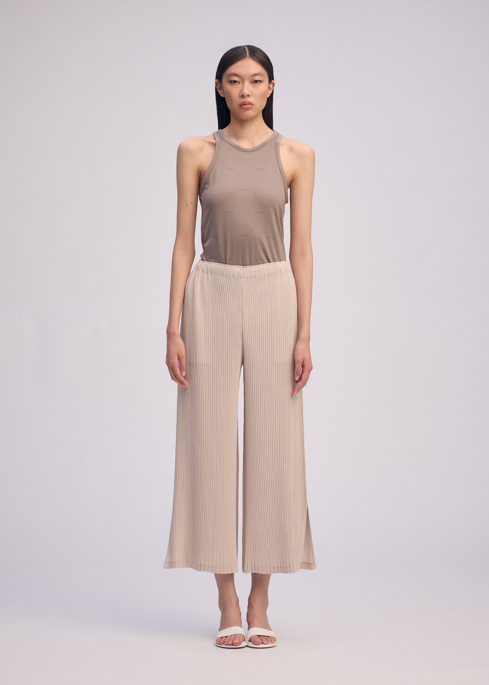 A model wears the Issey Miyake HATCHING BOTTOMS pants.