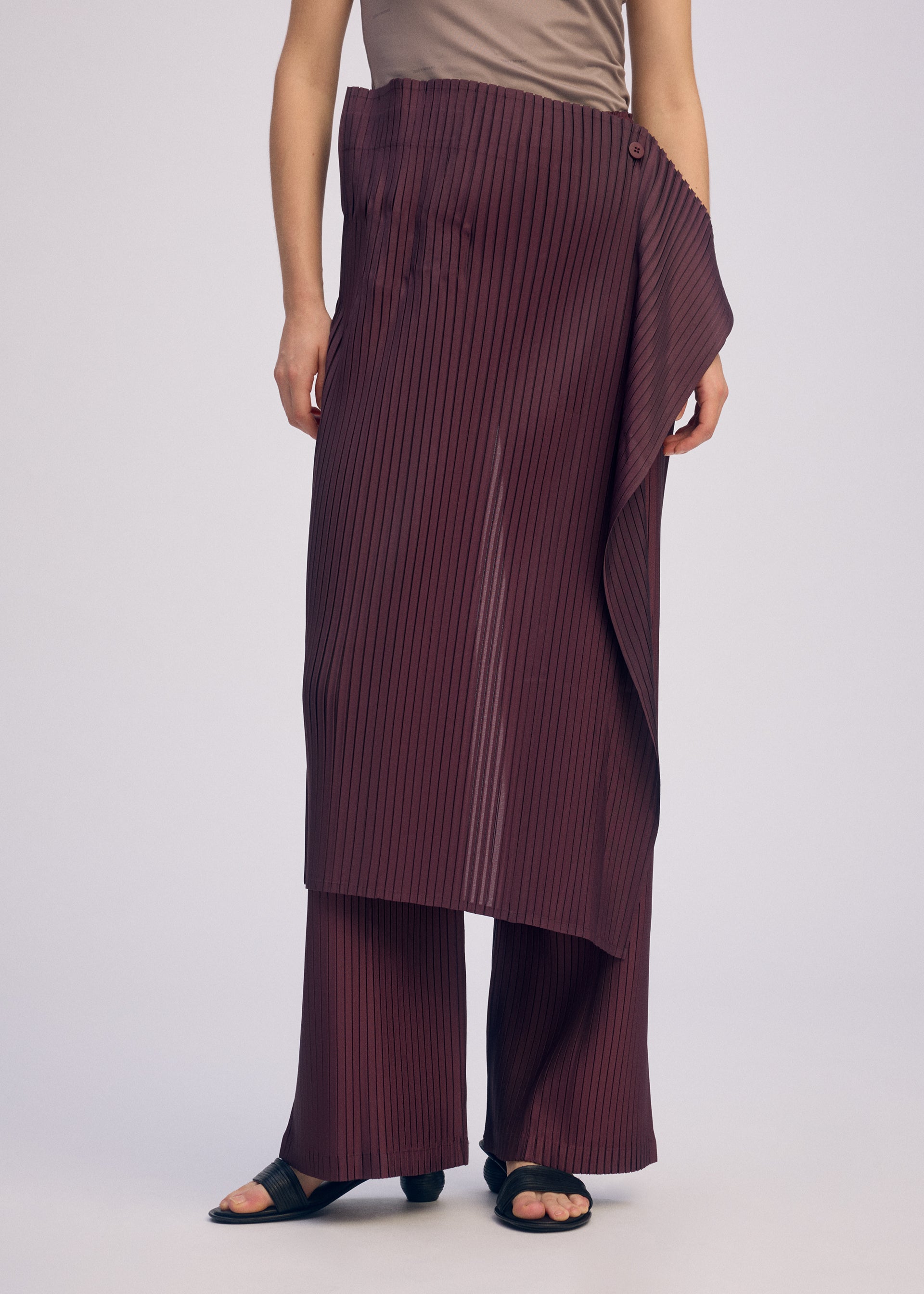 A model wears the ISSEY MIYAKE PLEATED ON PLEATS pants.