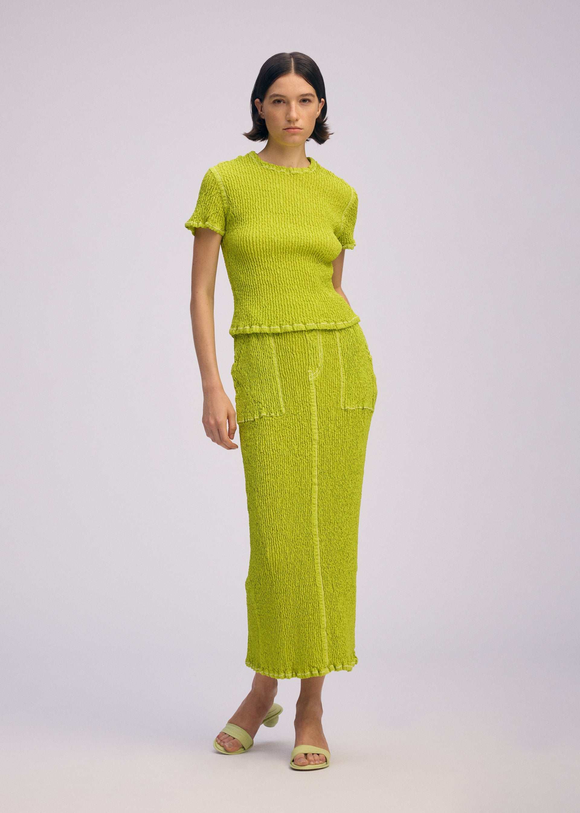 A model wears the ISSEY MIYAKE WAVELET ENSEMBLE skirt.