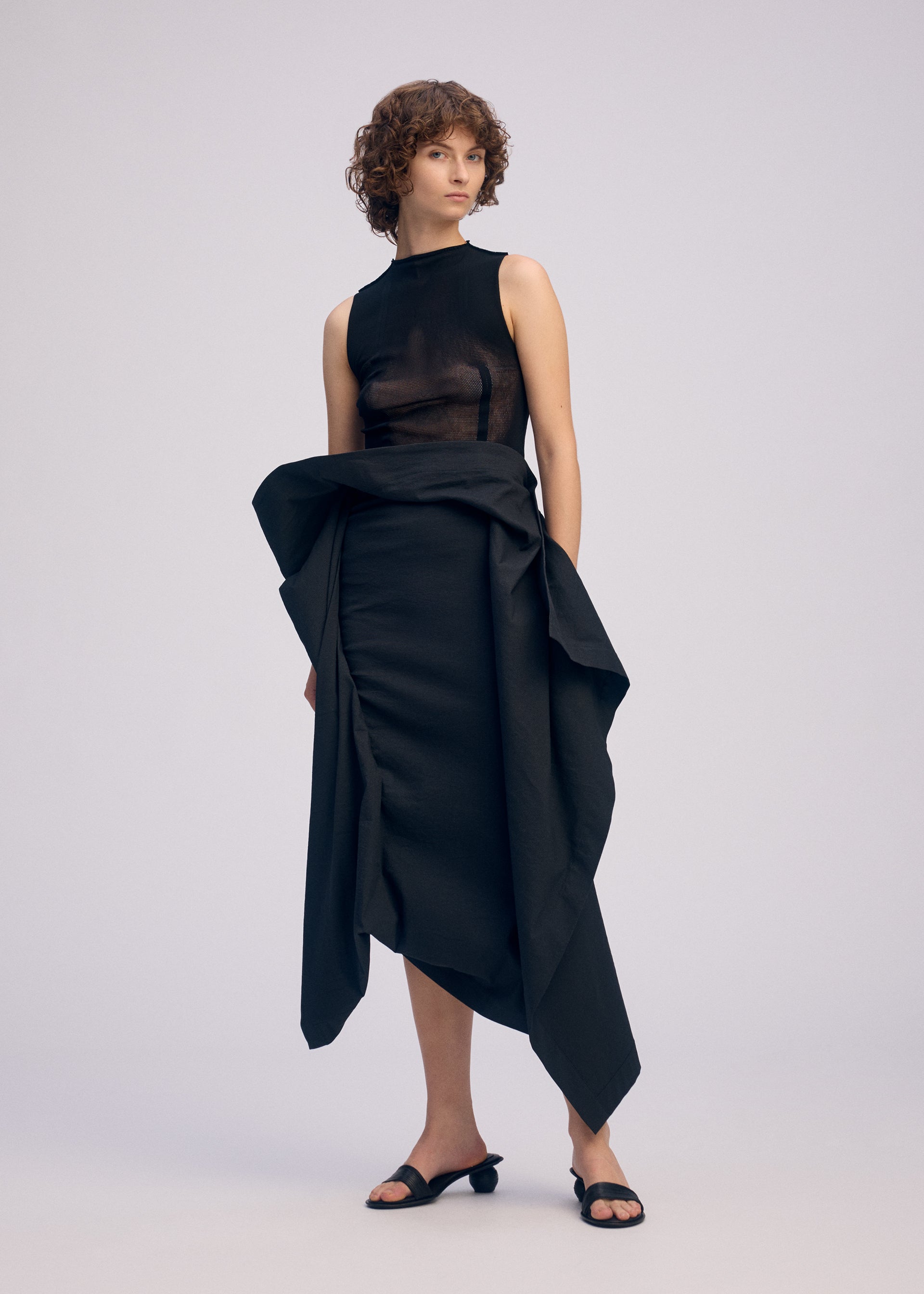 A model wears the ISSEY MIYAKE CONCEALED concealed-skirt-black.