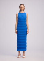 A model wears the ISSEY MIYAKE SPRING PLEATS spring-pleats-dress-chukar-beige-1.