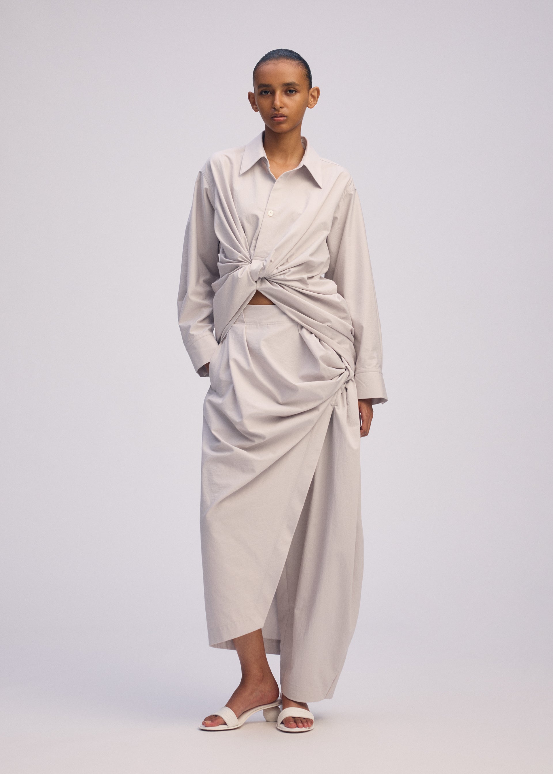 A model wears the ISSEY MIYAKE TWISTED DRAPE shirt.