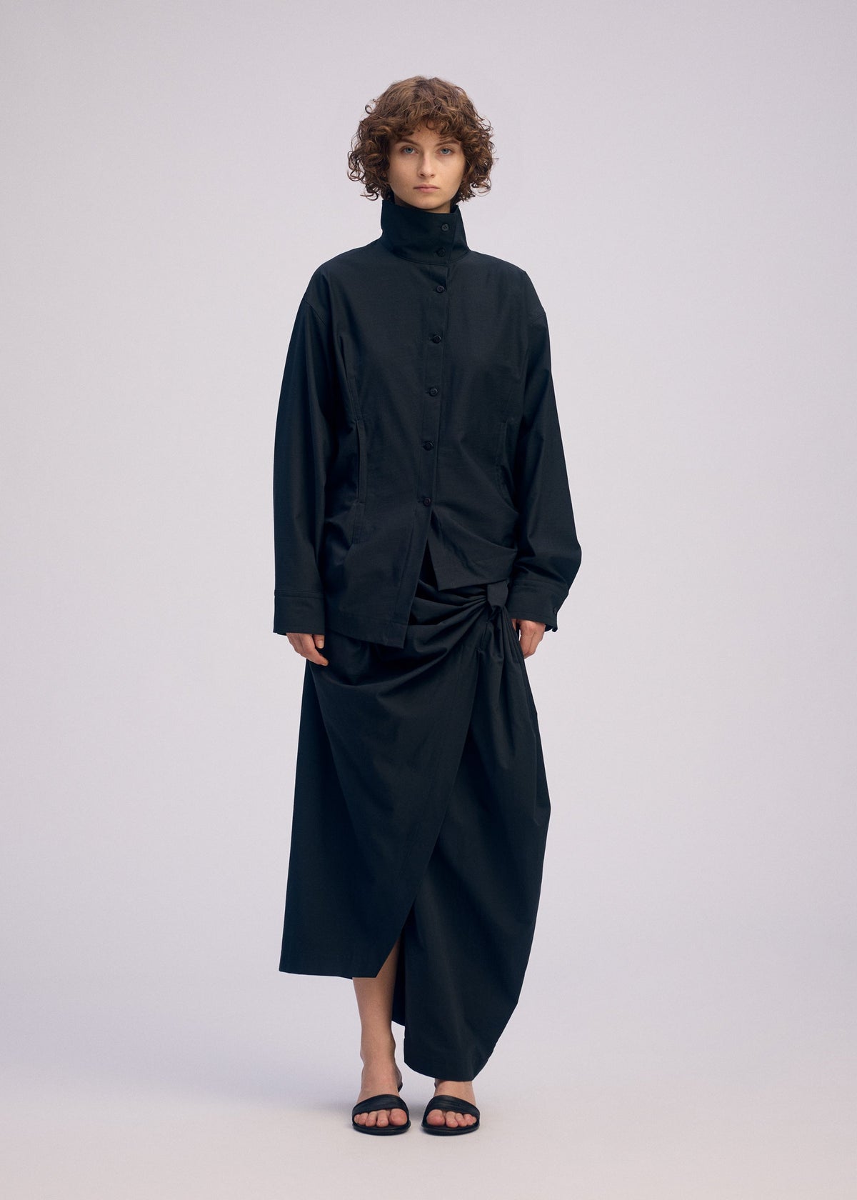 A model wears the ISSEY MIYAKE TWISTED DRAPE shirt.