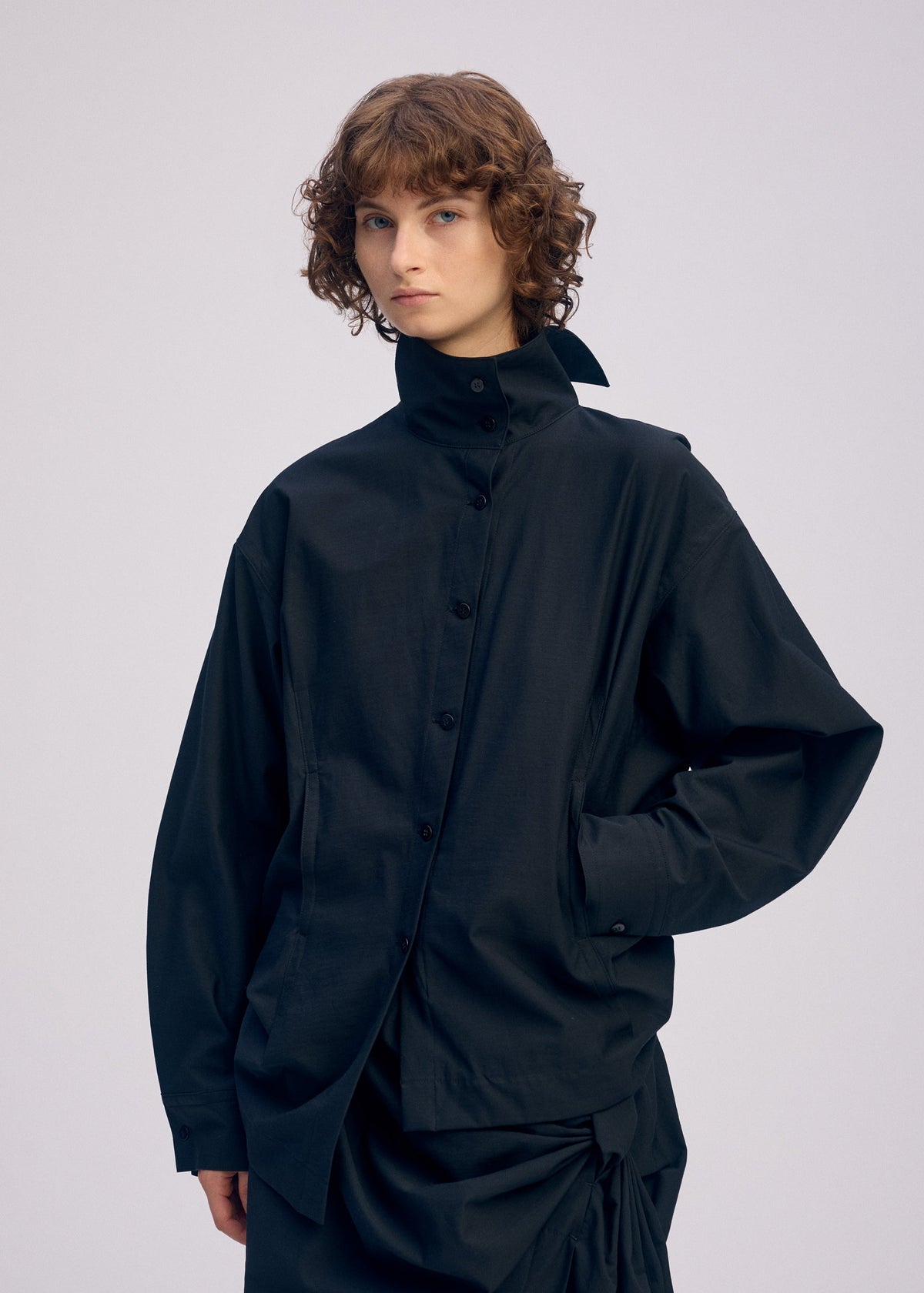 A model wears the ISSEY MIYAKE TWISTED DRAPE shirt.