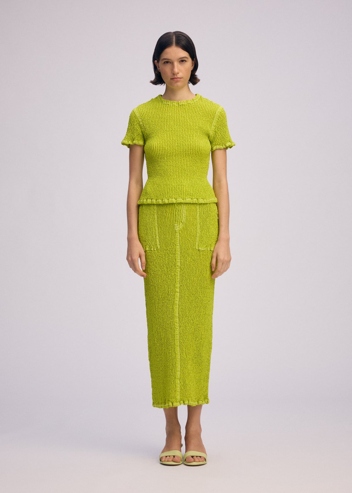 A model wears the ISSEY MIYAKE WAVELET ENSEMBLE shirt.