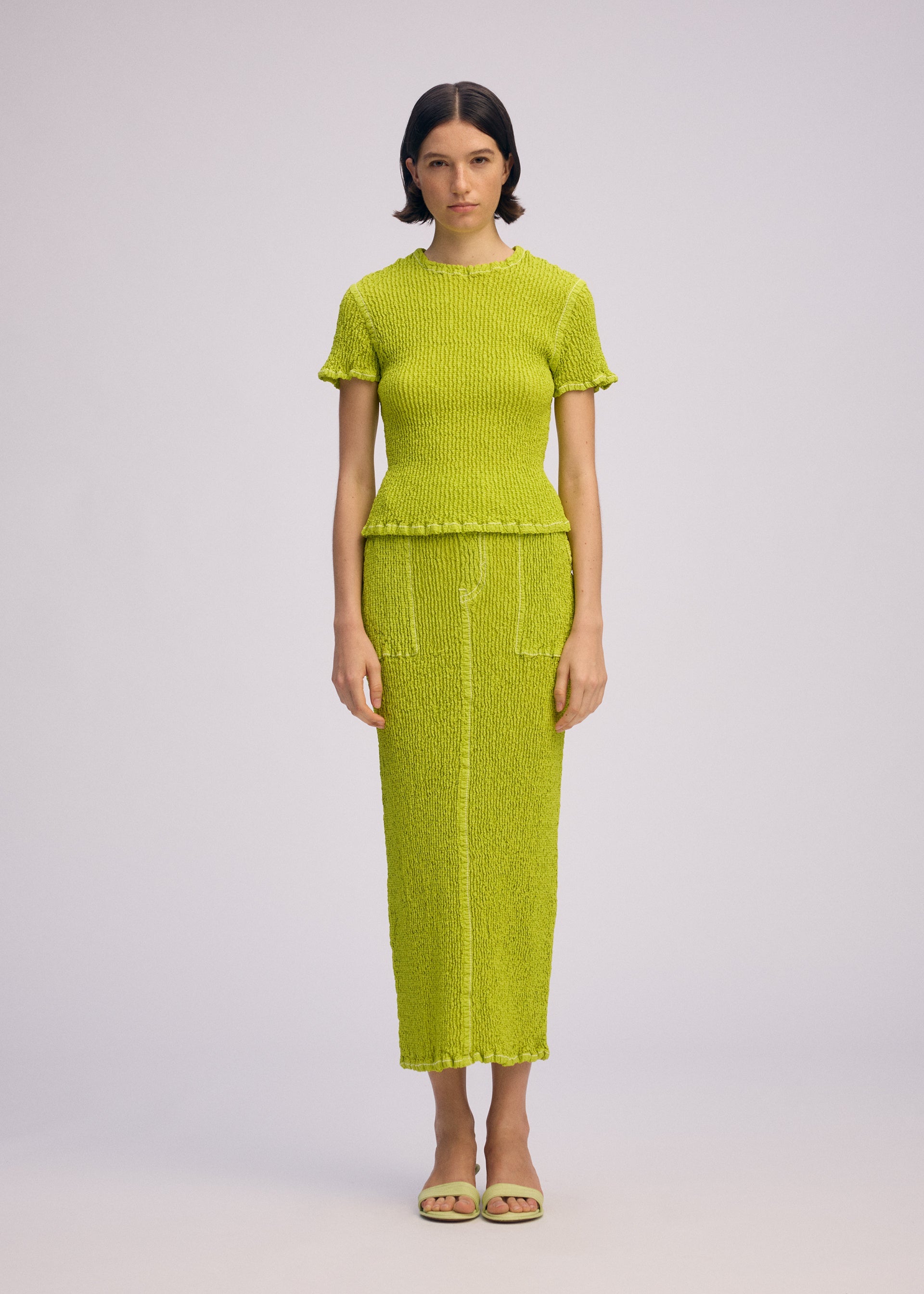 A model wears the ISSEY MIYAKE WAVELET ENSEMBLE shirt.