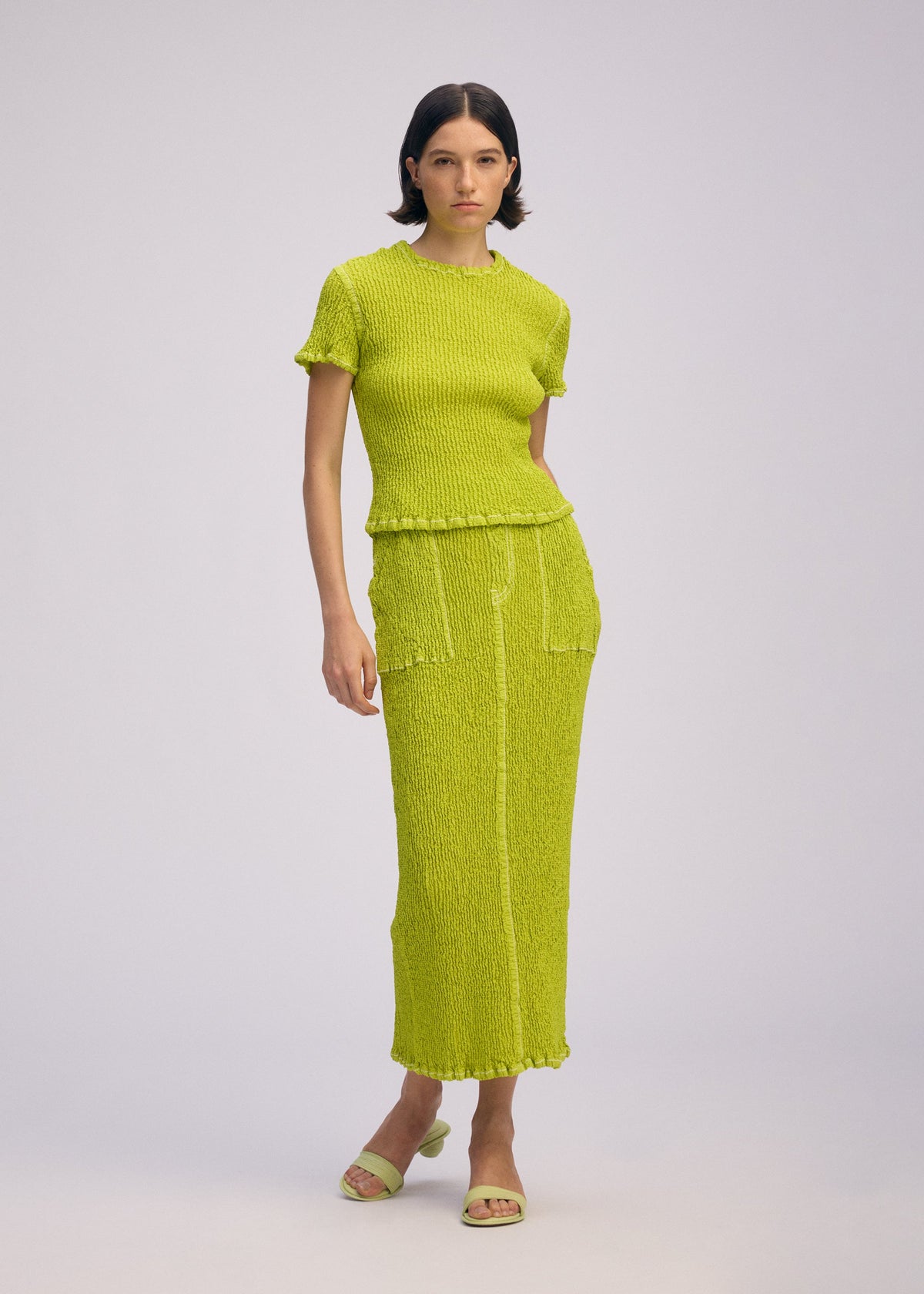 A model wears the ISSEY MIYAKE WAVELET ENSEMBLE shirt.