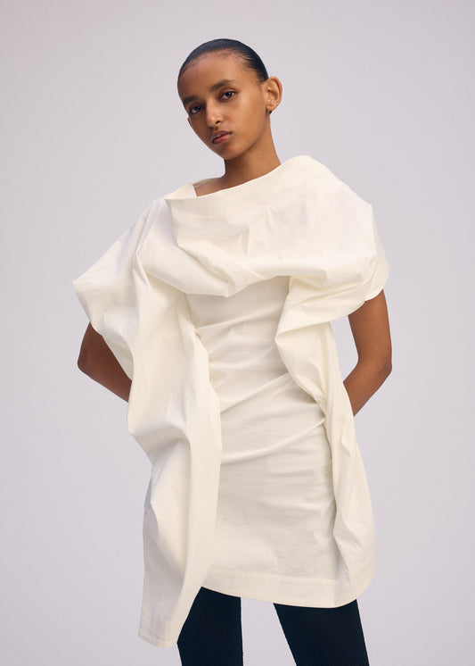 A model wears the ISSEY MIYAKE CONCEALED concealed-shirt-beige.