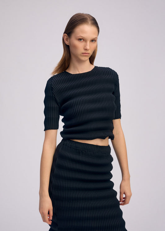A model wears the ISSEY MIYAKE SPRING PLEATS spring-pleats-shirt-chukar-beige.