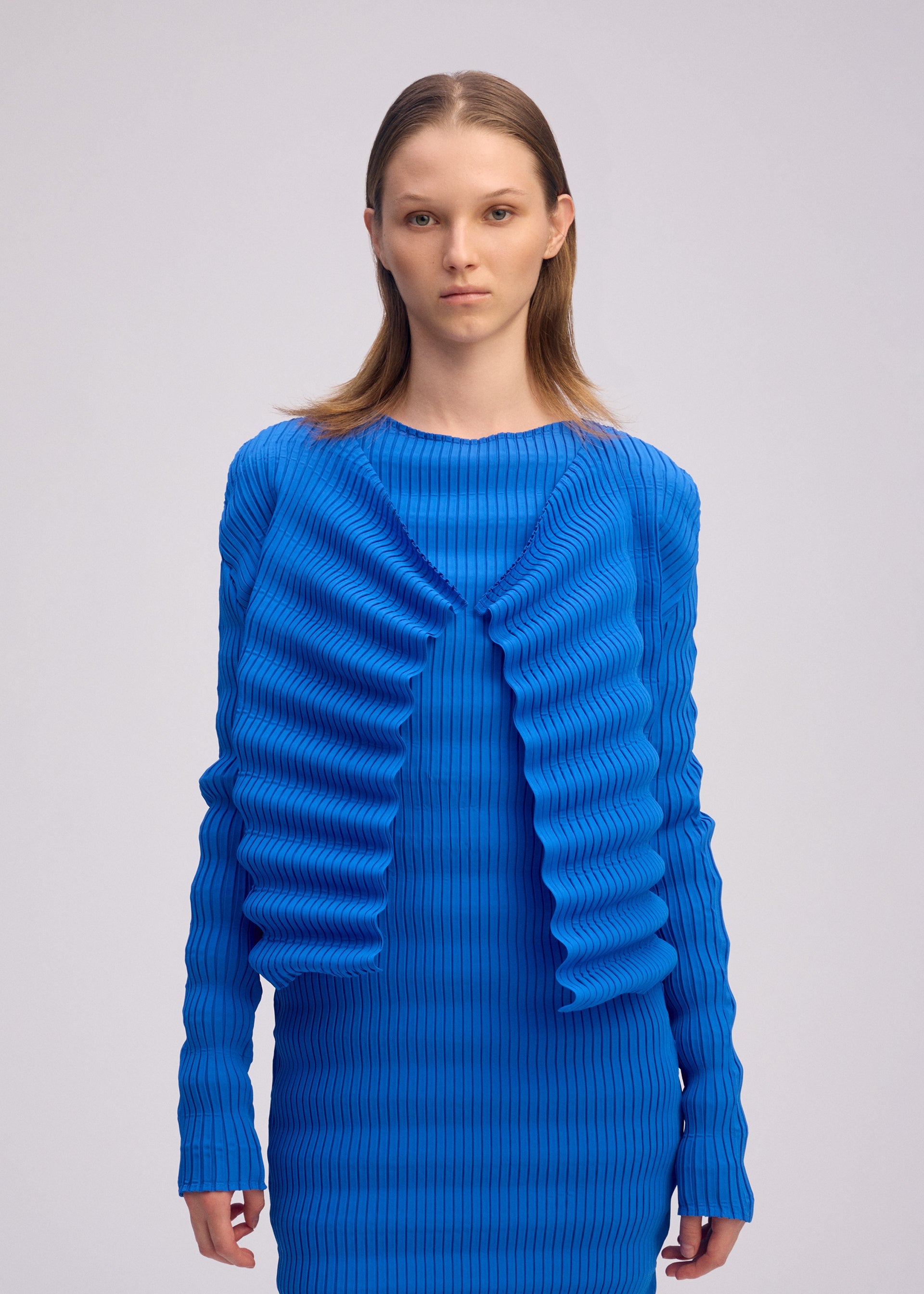 A model wears the ISSEY MIYAKE SPRING PLEATS spring-pleats-cardigan-chukar-beige.