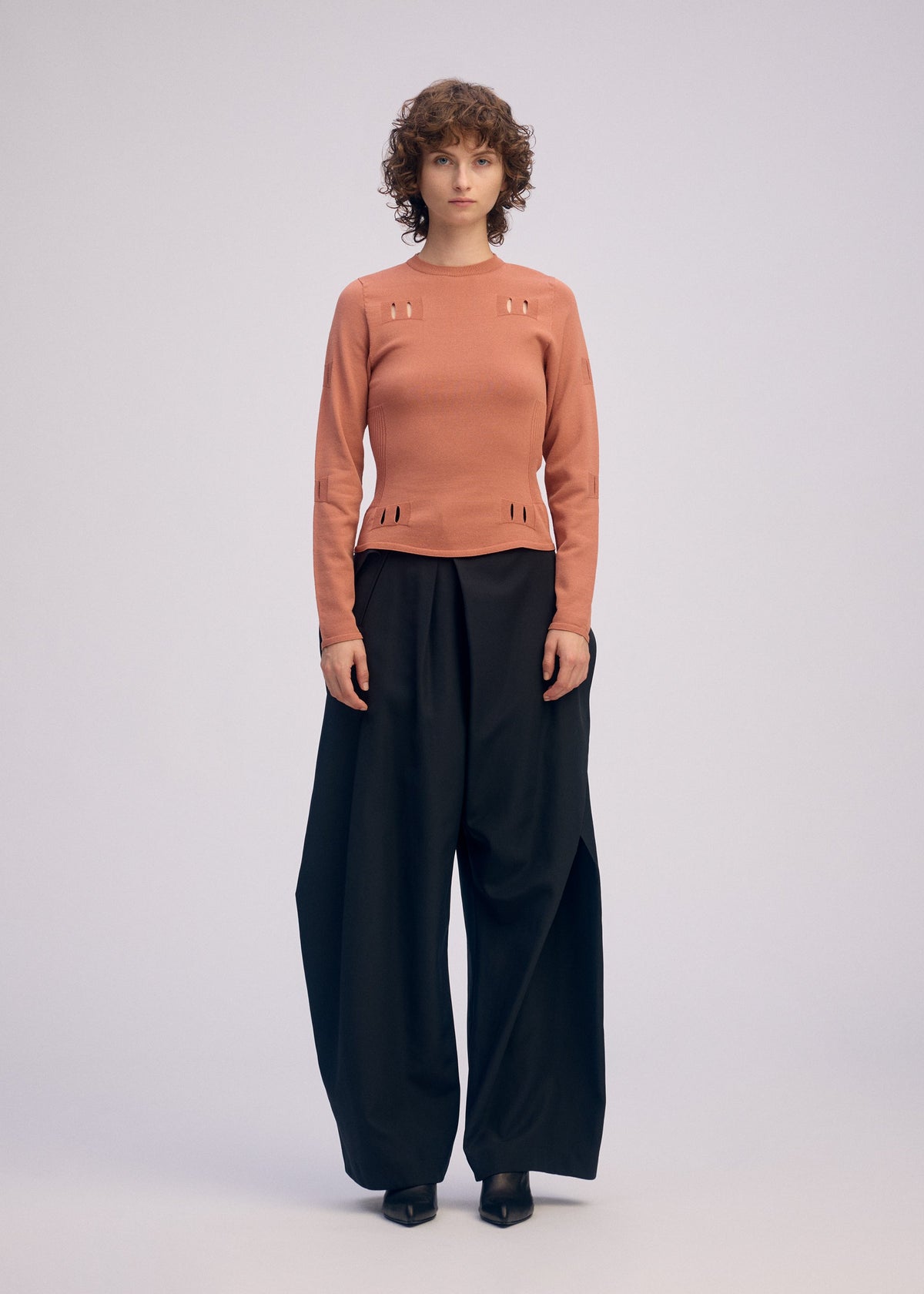 A model wears the ISSEY MIYAKE BELT LOOP KNIT top.