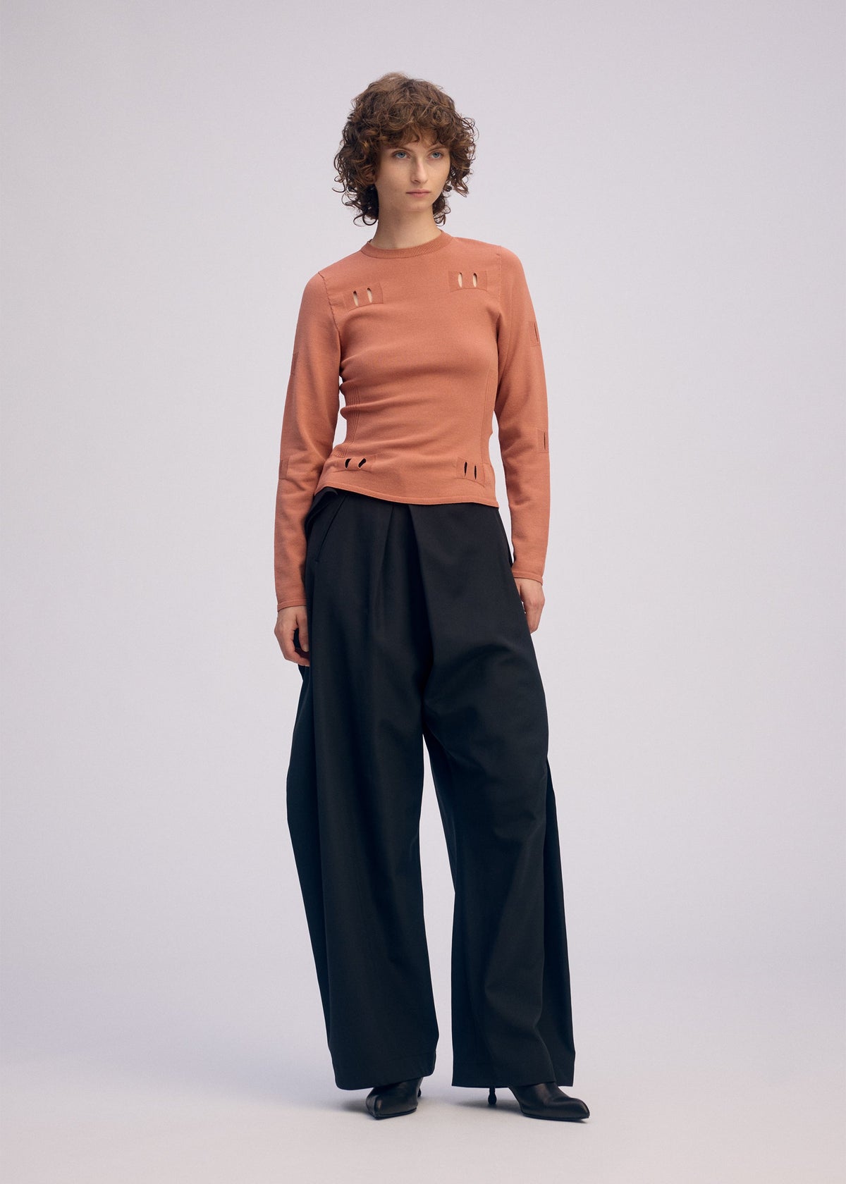 A model wears the ISSEY MIYAKE BELT LOOP KNIT top.