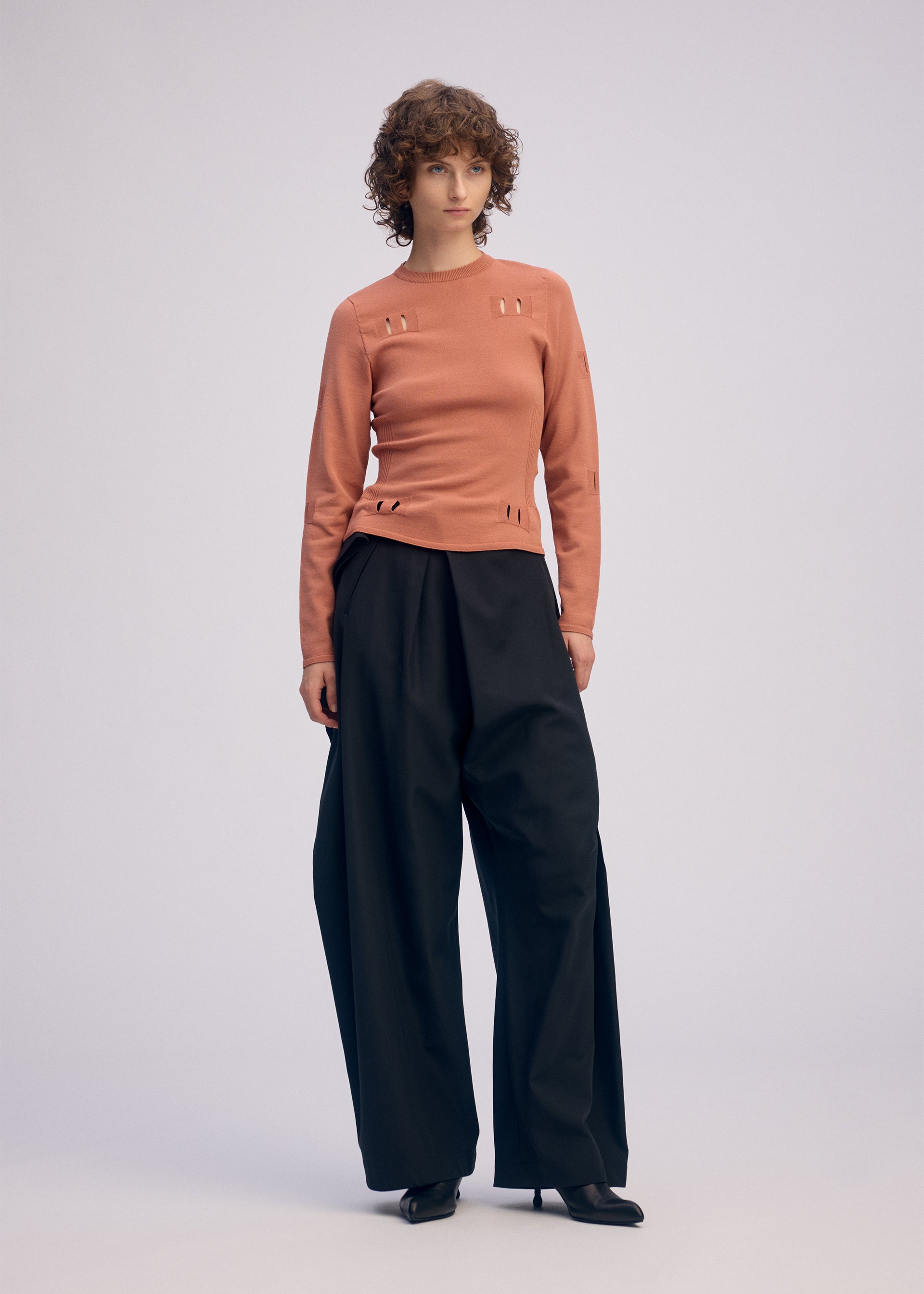 A model wears the ISSEY MIYAKE BELT LOOP KNIT top.