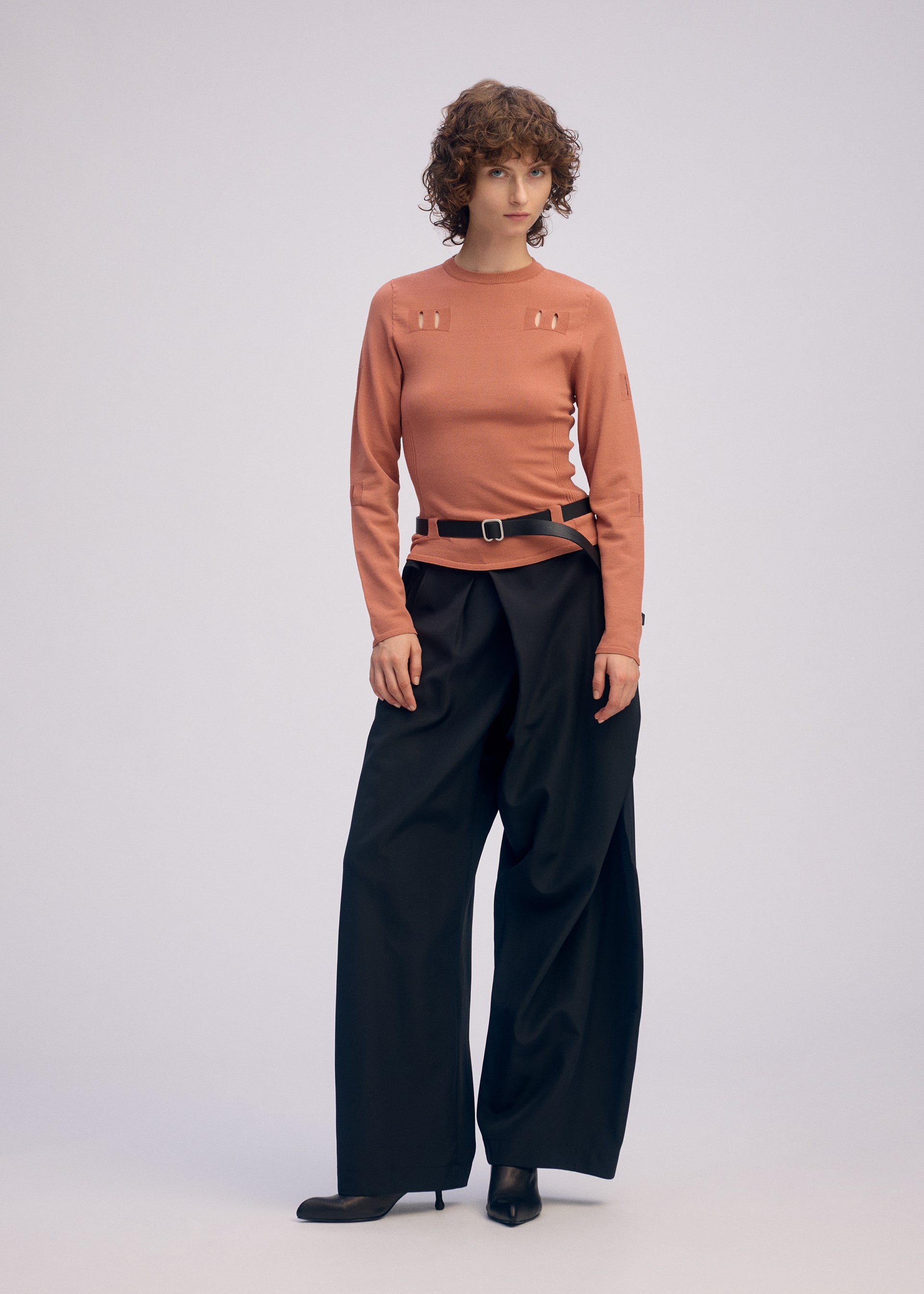 A model wears the ISSEY MIYAKE BELT LOOP KNIT top.