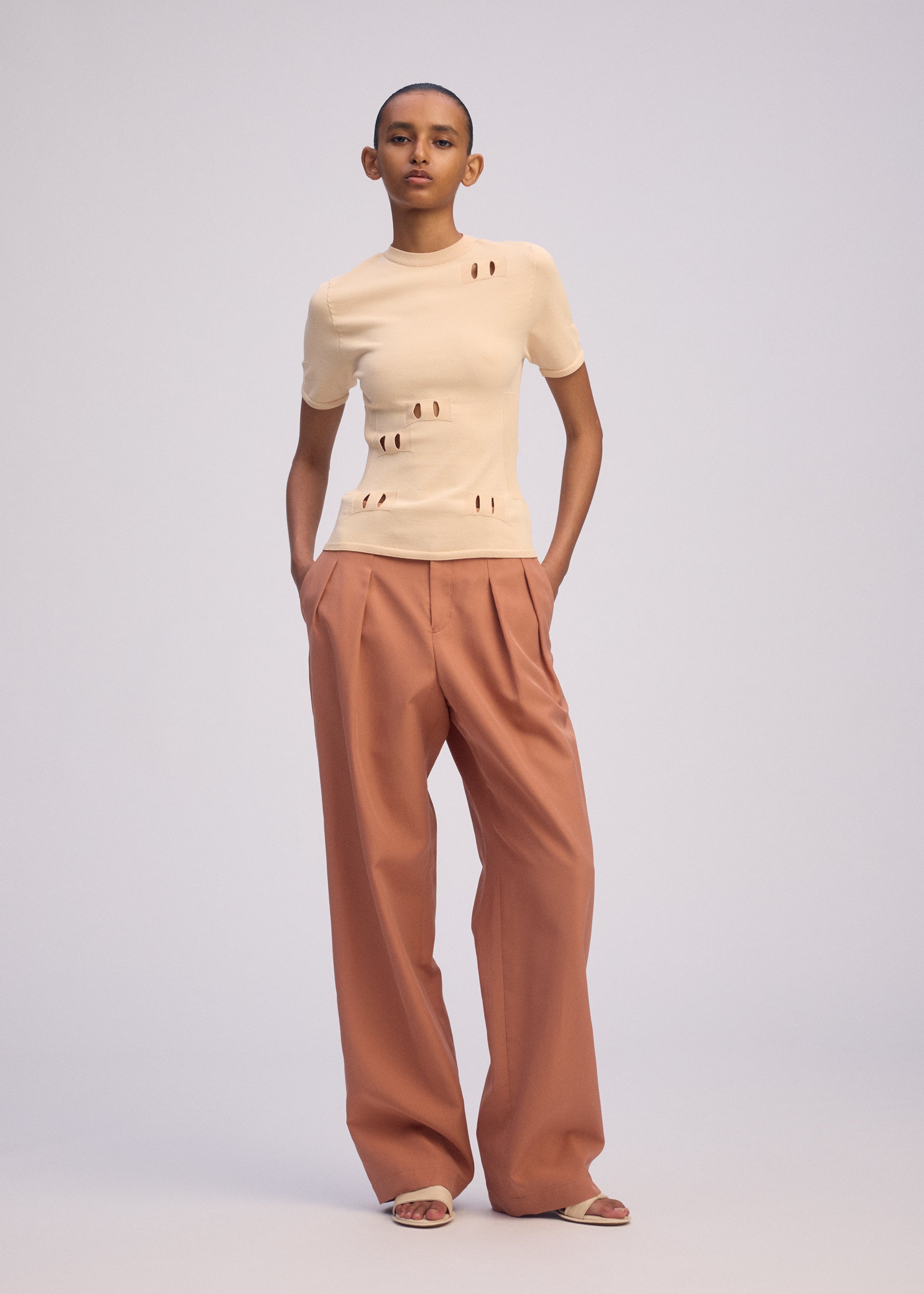 A model wears the ISSEY MIYAKE BELT LOOP KNIT top.