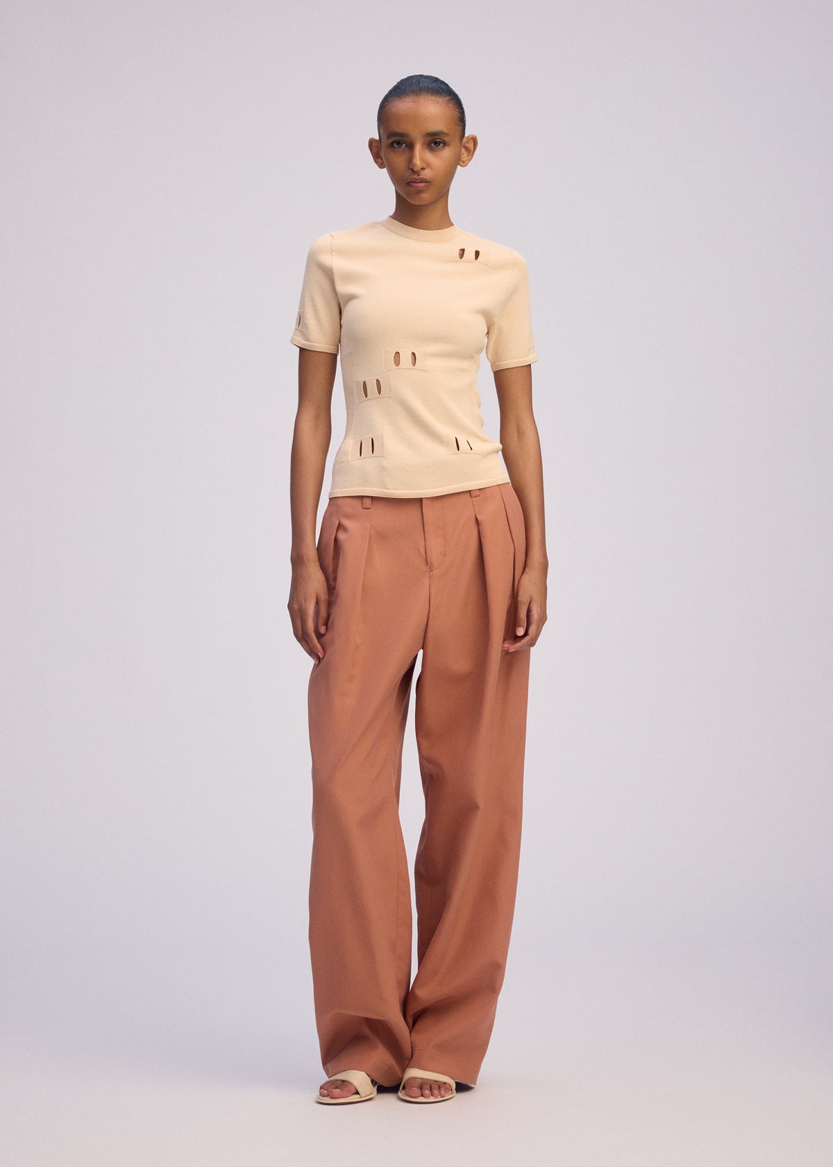 A model wears the ISSEY MIYAKE BELT LOOP KNIT top.