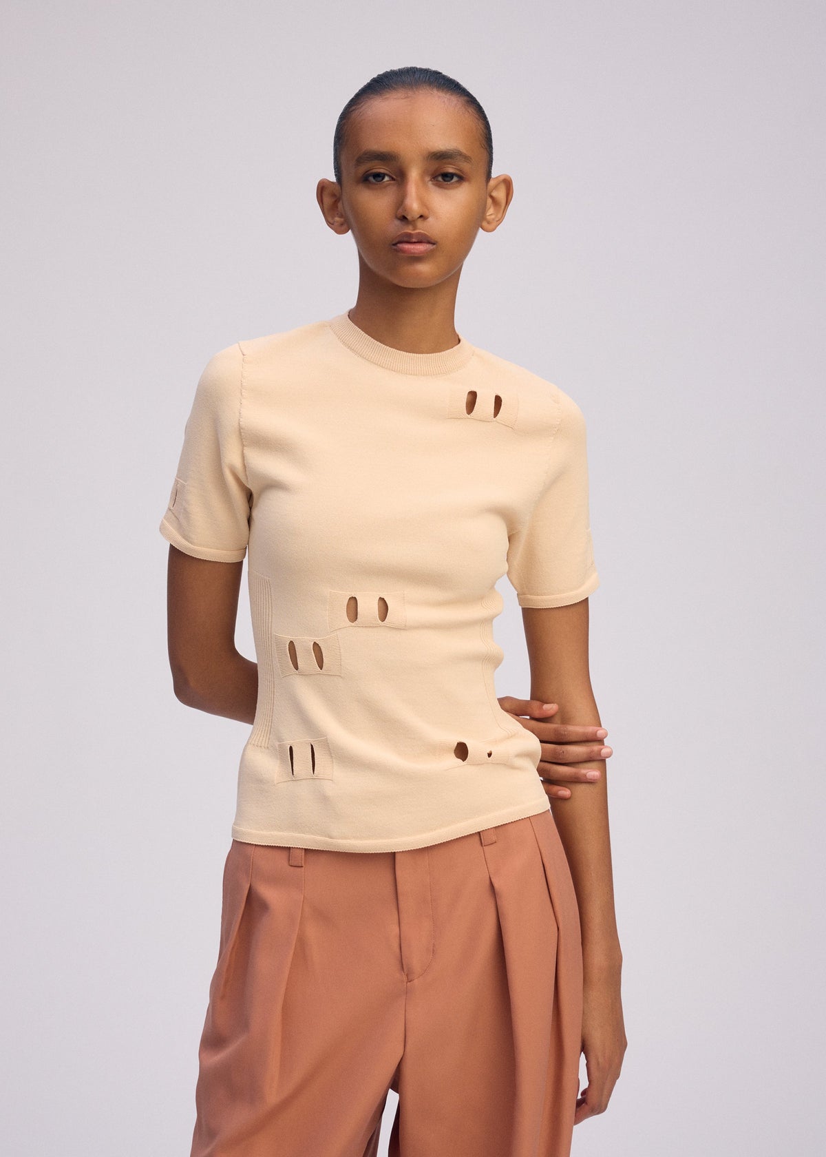 A model wears the ISSEY MIYAKE BELT LOOP KNIT top.