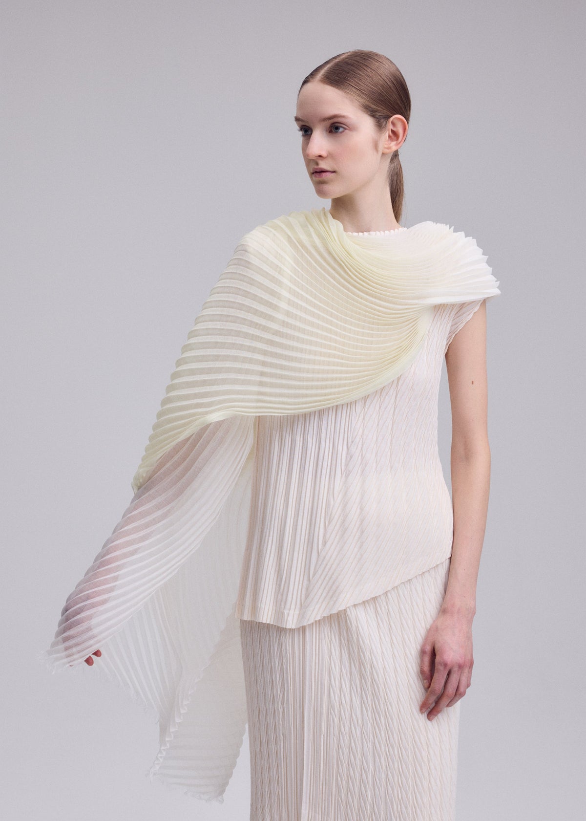 A model wears the ISSEY MIYAKE GRADATION RAMIE PLEATS STOLE gradation-ramie-pleats-stole-stole-black-hued-1.
