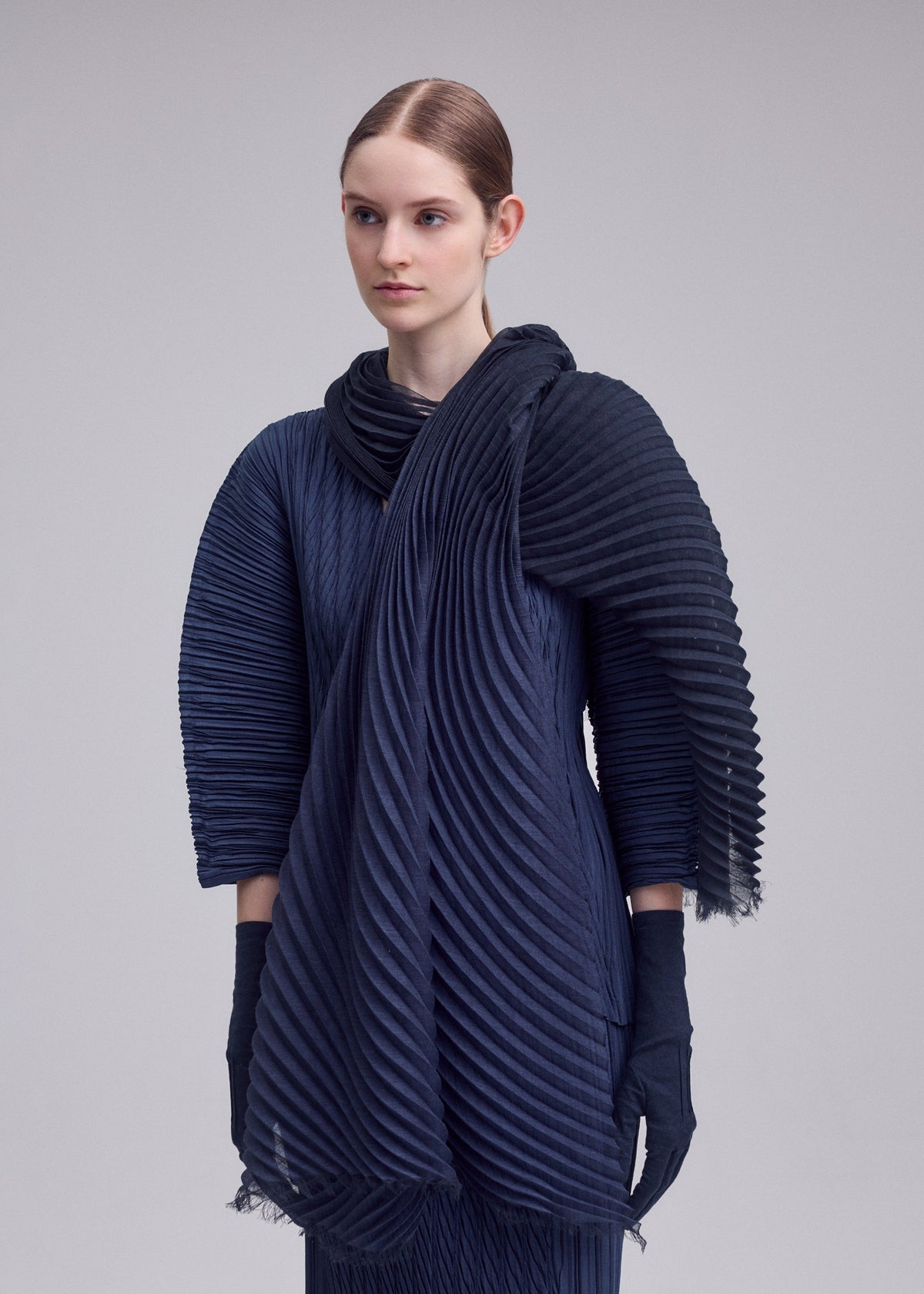 A model wears the ISSEY MIYAKE GRADATION RAMIE PLEATS STOLE gradation-ramie-pleats-stole-stole-black-hued-1.