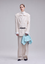 A model wears the ISSEY MIYAKE SQUARE BAG(LEATHER) bag.