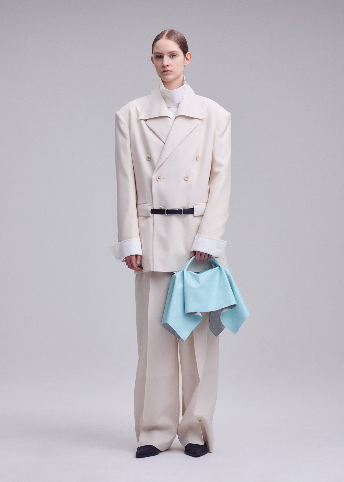 A model wears the ISSEY MIYAKE SQUARE BAG(LEATHER) bag.