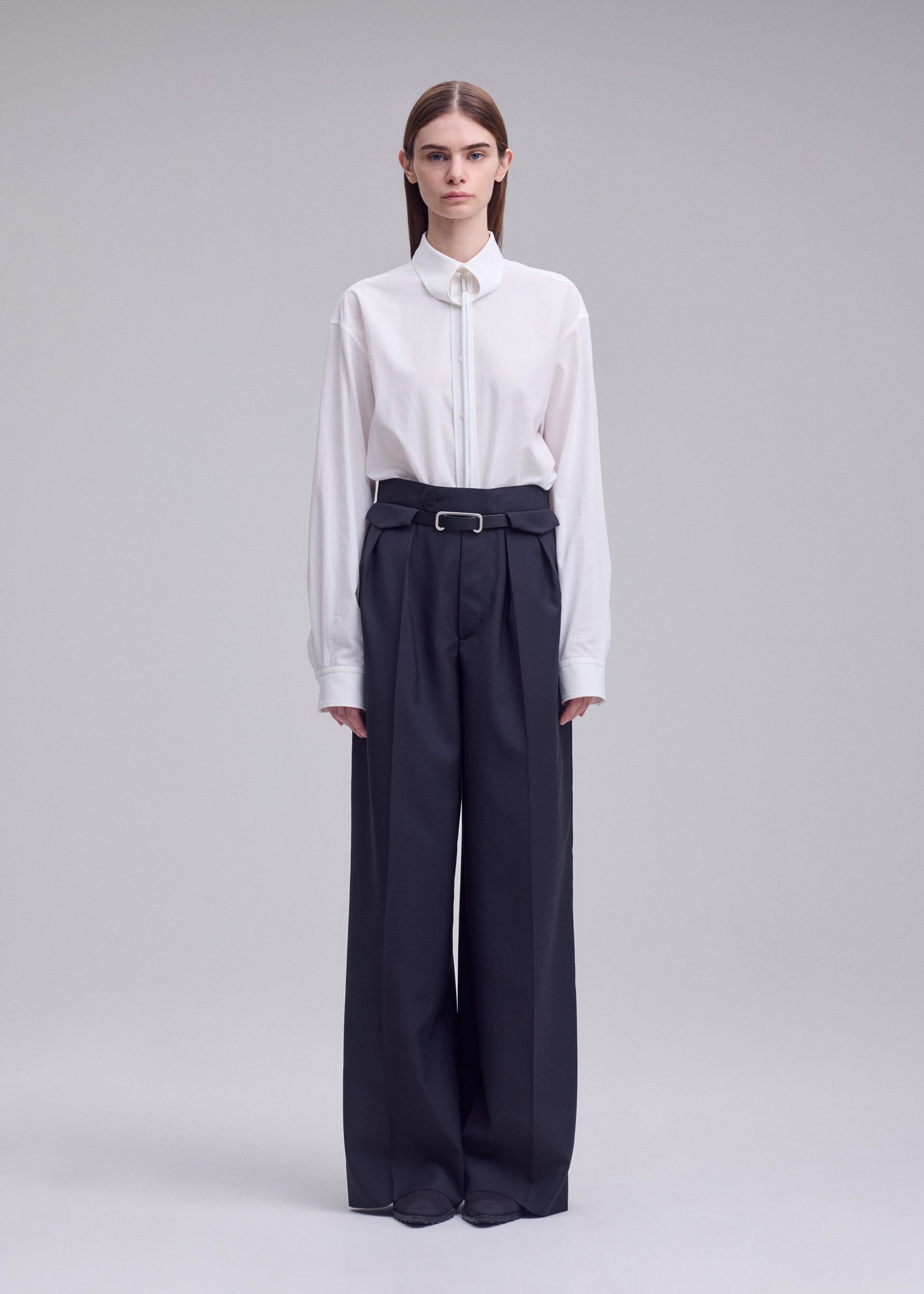 A model wears the ISSEY MIYAKE HONEST ENSEMBLE honest-ensemble-trousers-black.