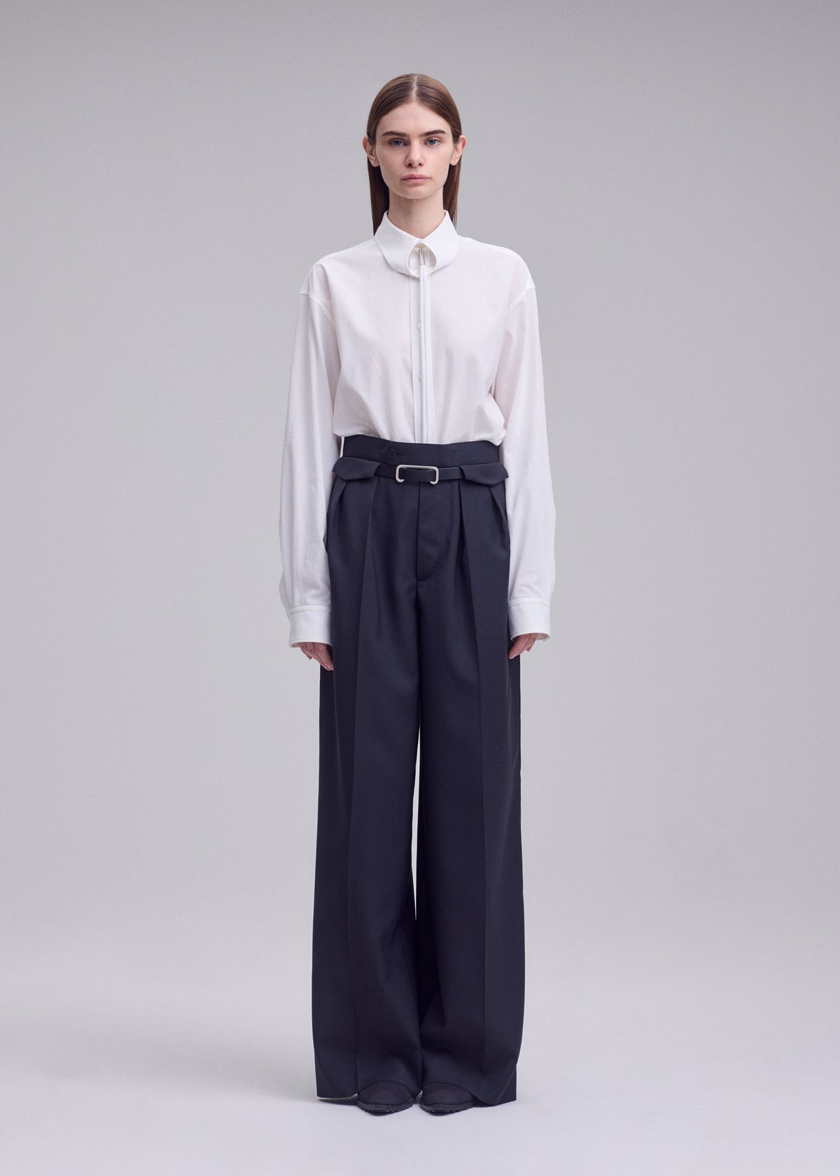 A model wears the ISSEY MIYAKE HONEST ENSEMBLE honest-ensemble-trousers-grey.