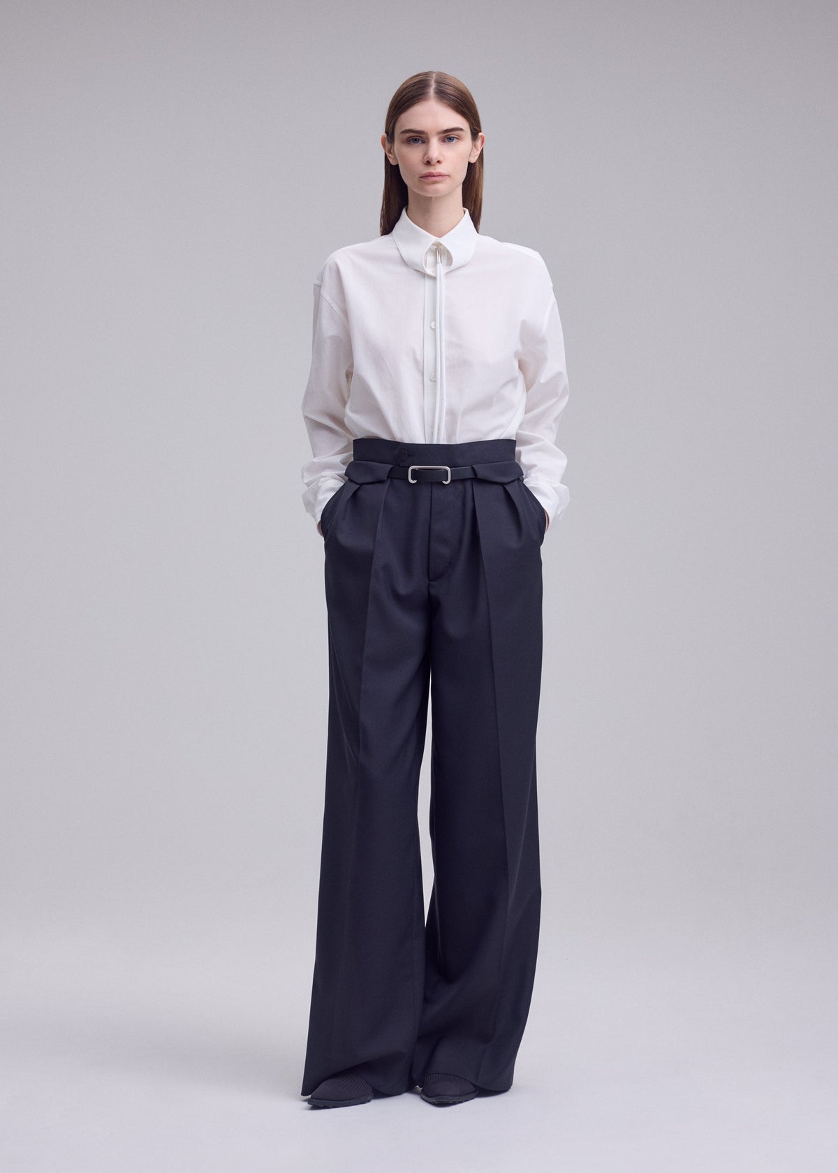 A model wears the ISSEY MIYAKE HONEST ENSEMBLE honest-ensemble-trousers-grey.