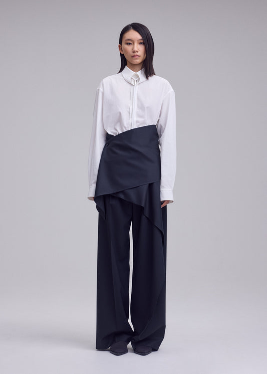 A model wears the ISSEY MIYAKE LUSTROUS WOOL PANTS trousers.