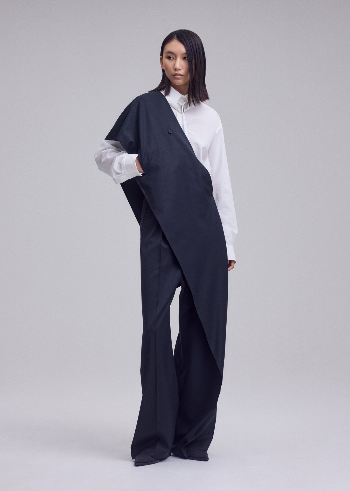 A model wears the ISSEY MIYAKE LUSTROUS WOOL PANTS trousers.